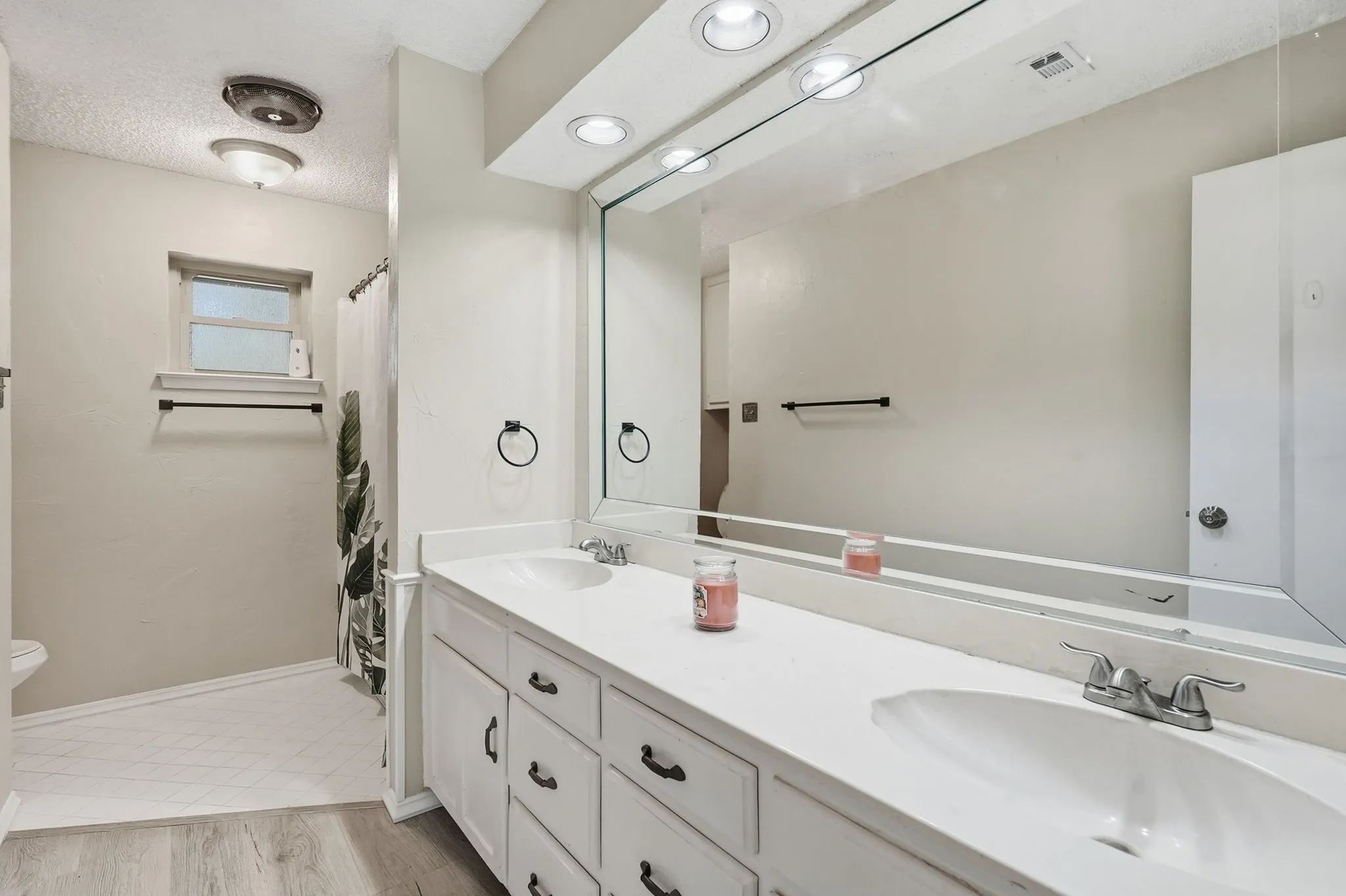 Double vanity with white cabinetry and integrated sinks, illuminated by recessed lighting