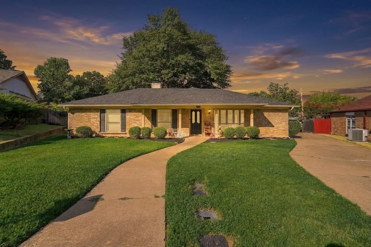 Brick exterior with dark shutters, a curved concrete walkway, and a landscaped front yard