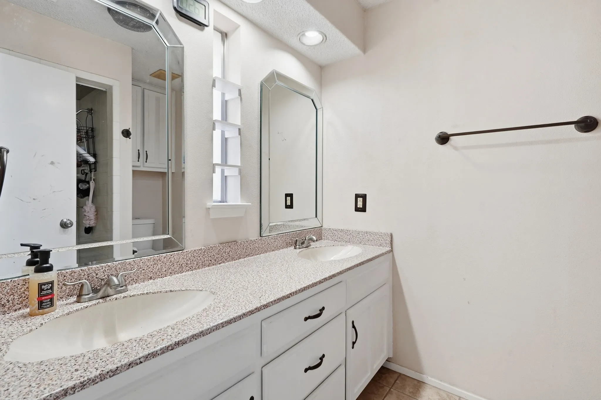 Dual vanity with integrated sinks, speckled countertop, and white cabinetry