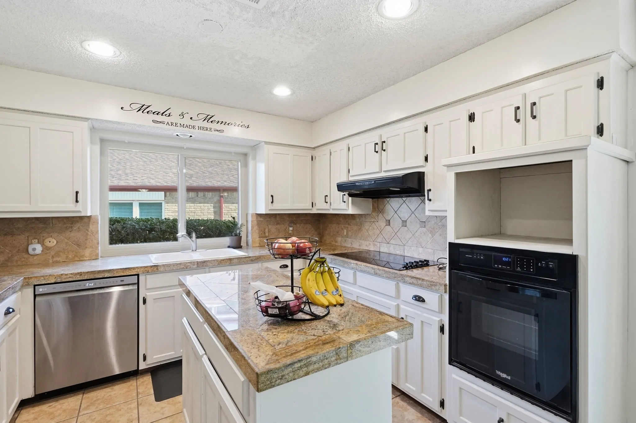 White cabinetry with dark hardware, stone countertops, stainless steel dishwasher, built-in oven, and a tiled backsplash