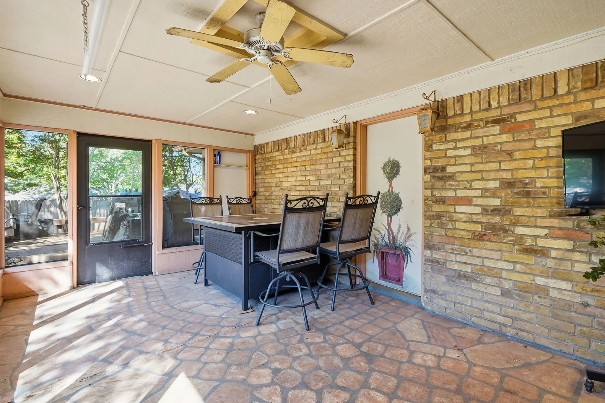 Enclosed patio featuring a ceiling fan, recessed lighting, stone-finish flooring, and brick accent walls