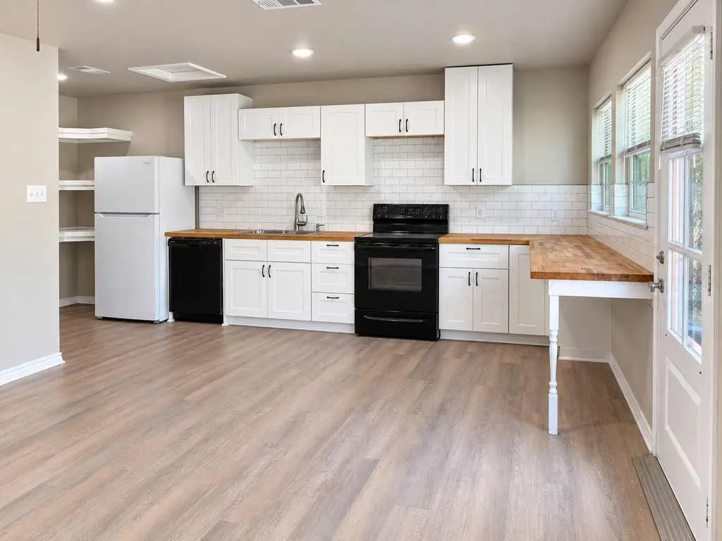 White cabinetry, butcher-block countertops, subway-tile backsplash and contrasting black appliances.