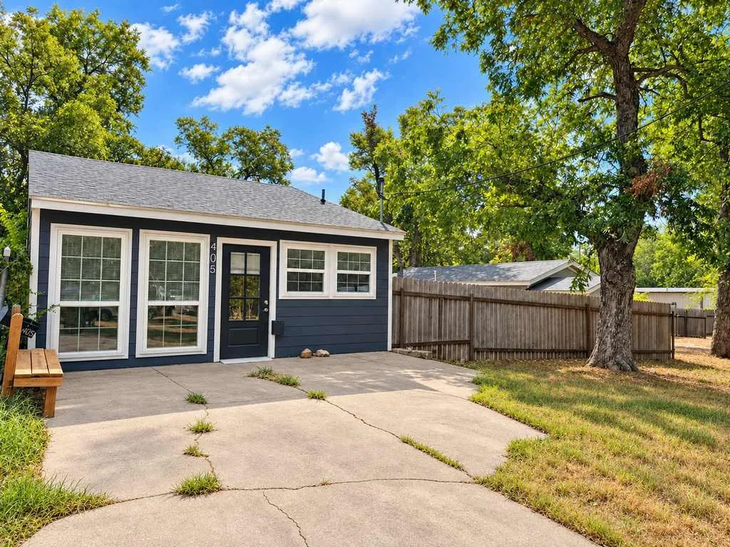 Charming cottage-style exterior with mature shade trees and off-street parking.