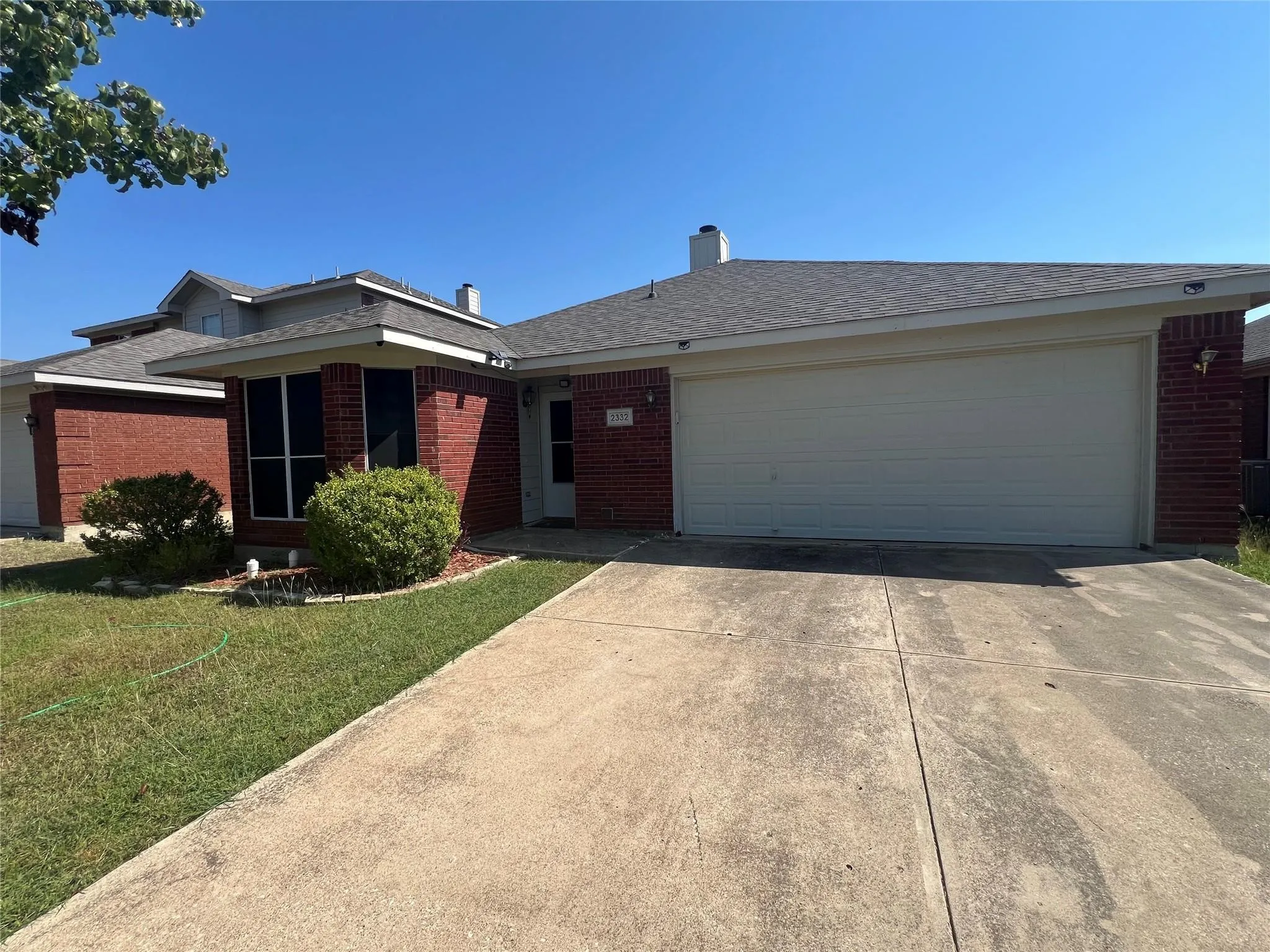 Red brick facade with a two-car garage and concrete driveway
