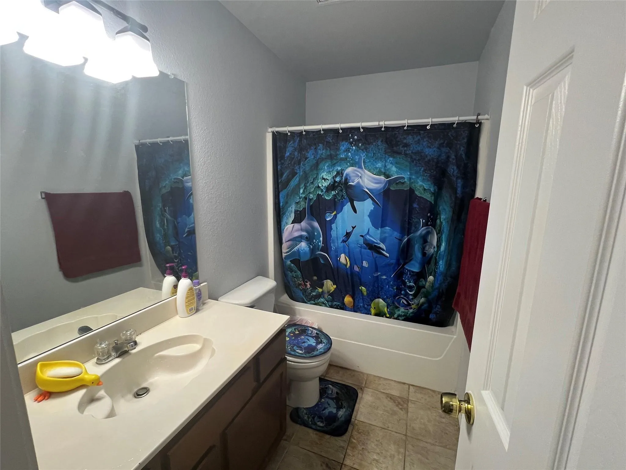 White paneled door, flush mount vanity lighting, wall-mounted mirror, single vanity with integrated sink, and white bathtub with shower rod