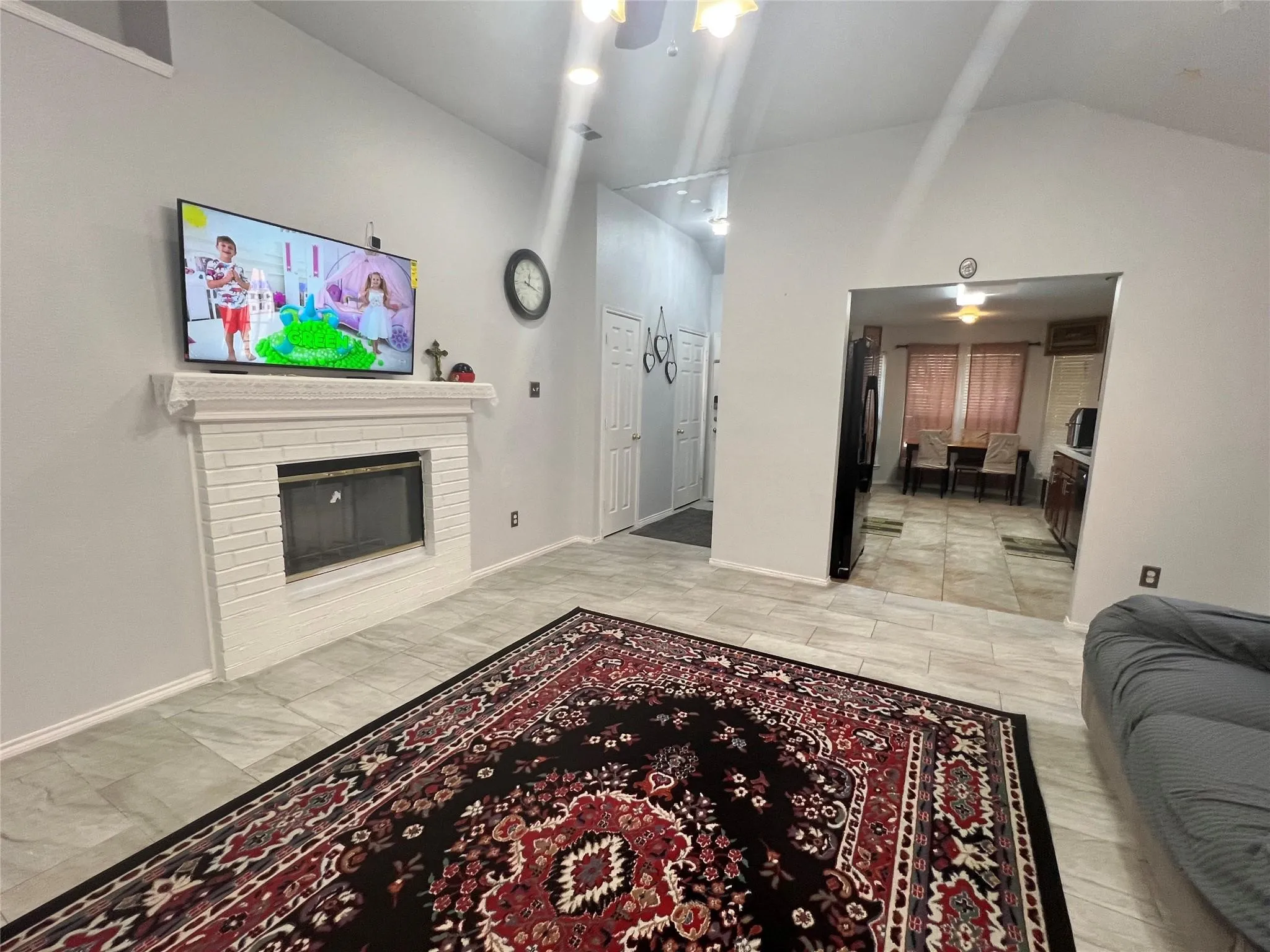 Vaulted ceiling, recessed lighting, white brick fireplace, tile flooring, and arched doorway