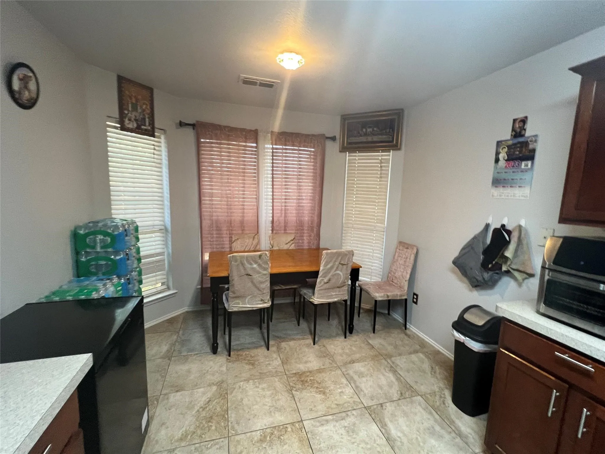 Tile flooring, bay window with blinds, recessed lighting, ceiling-mounted light fixture, and wood cabinetry