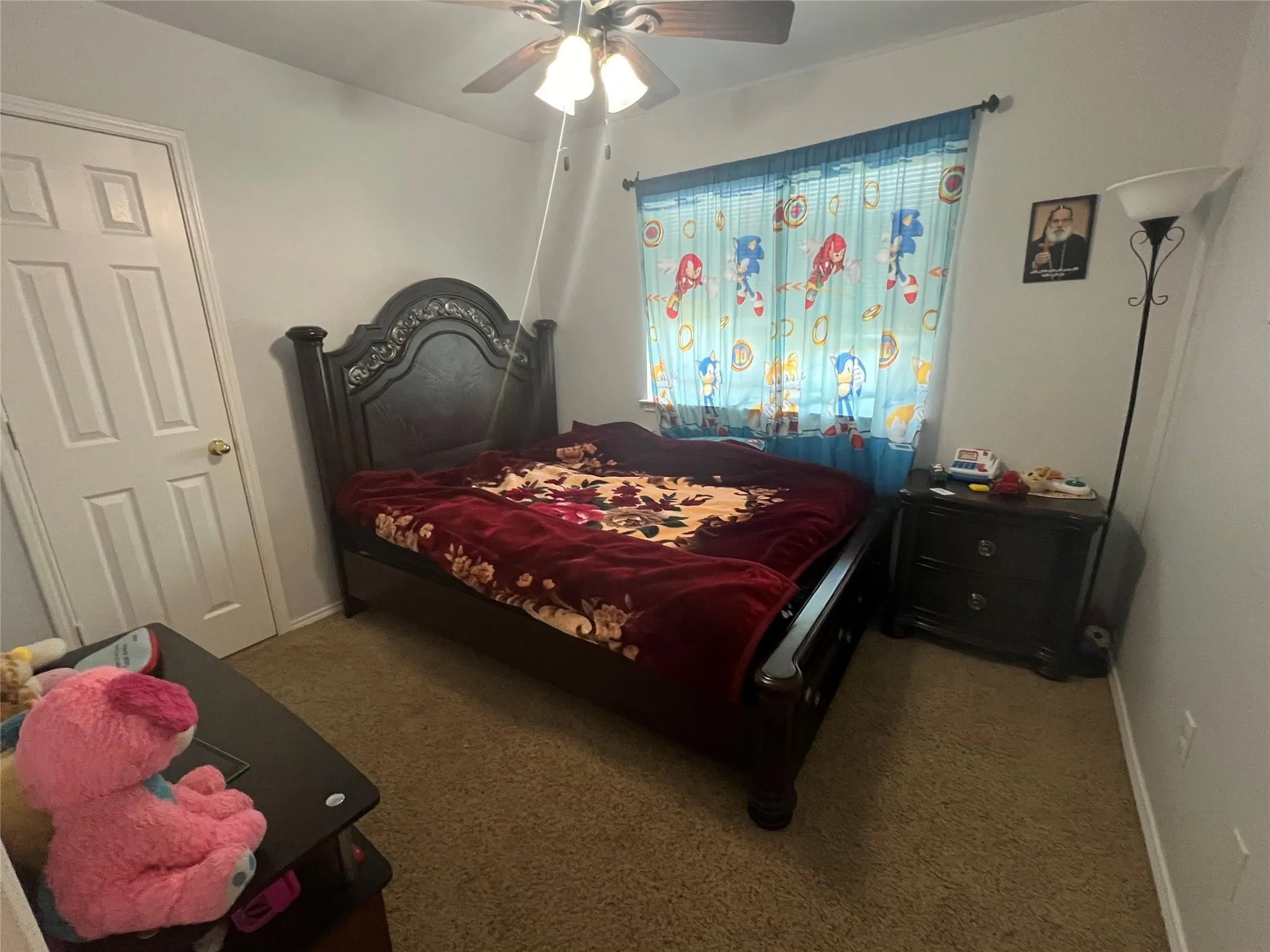 Carpeted room with a ceiling fan light fixture and a multi-panel door