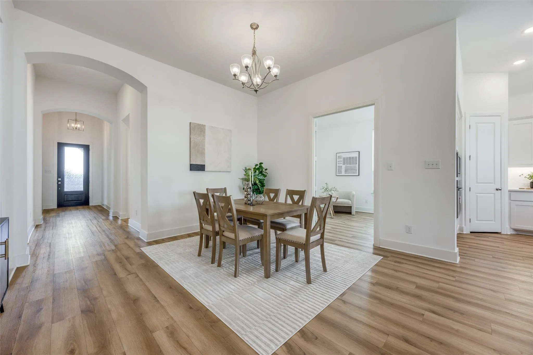 Dining area featuring arched walkways, a chandelier, light wood-style floors, and recessed lighting
