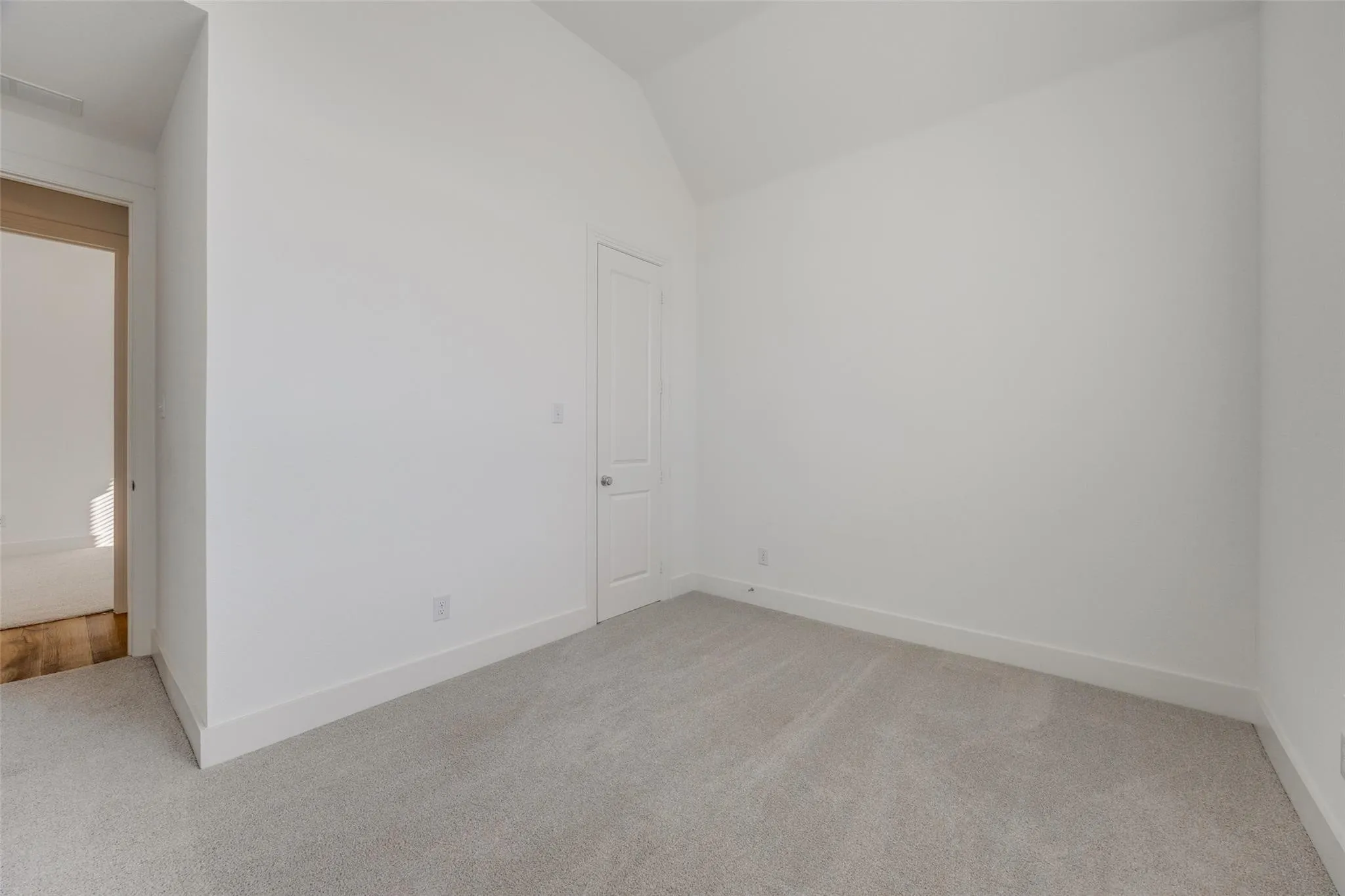 Unfurnished room with light colored carpet and vaulted ceiling