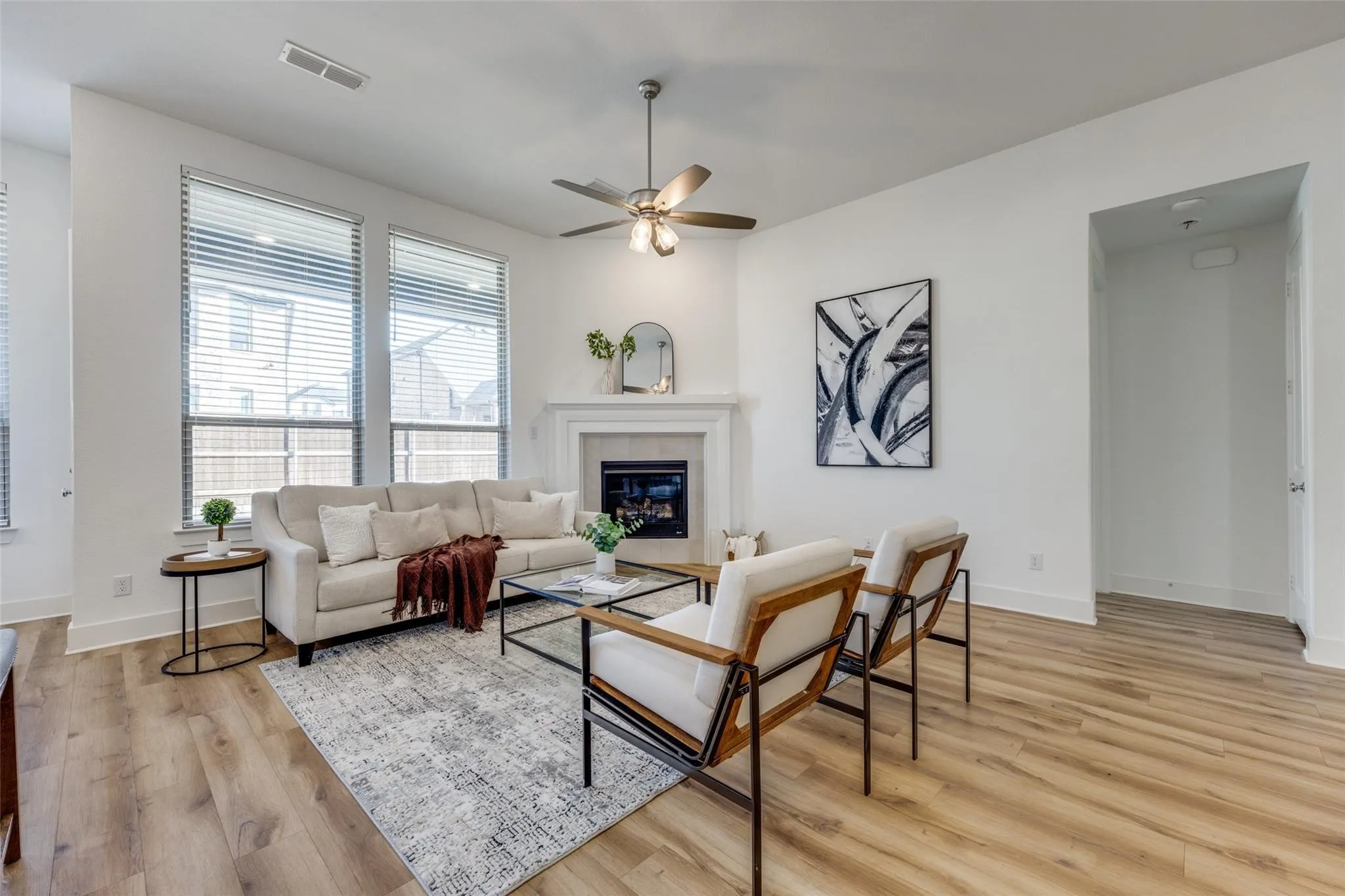 Living area featuring light wood finished floors, ceiling fan, and a tile fireplace