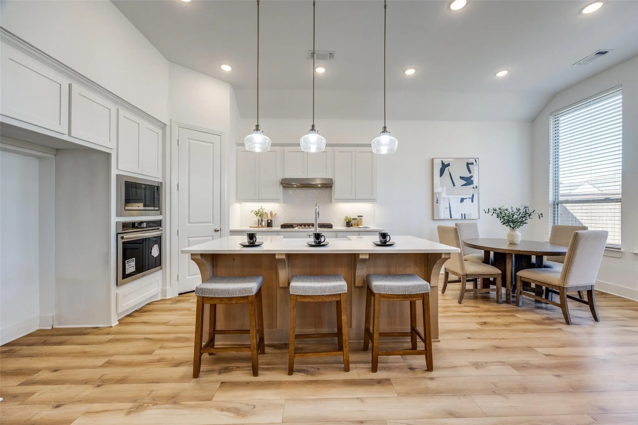 Kitchen with stainless steel appliances, light countertops, under cabinet range hood, an island with sink, and a breakfast bar