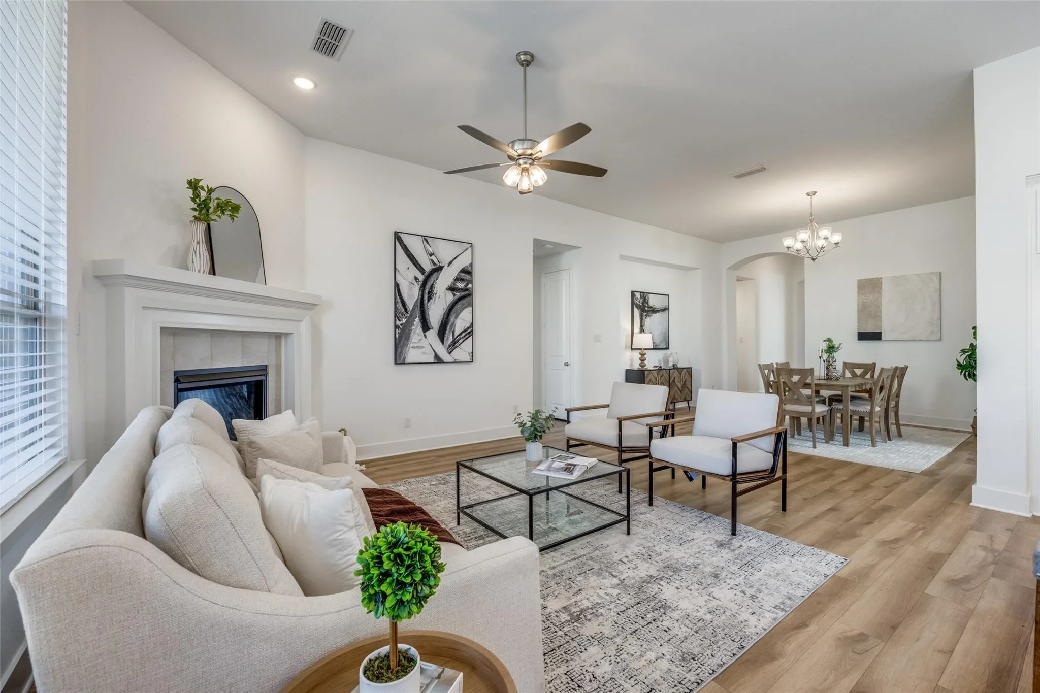 Living room with light wood finished floors, a fireplace, arched walkways, ceiling fan, and recessed lighting