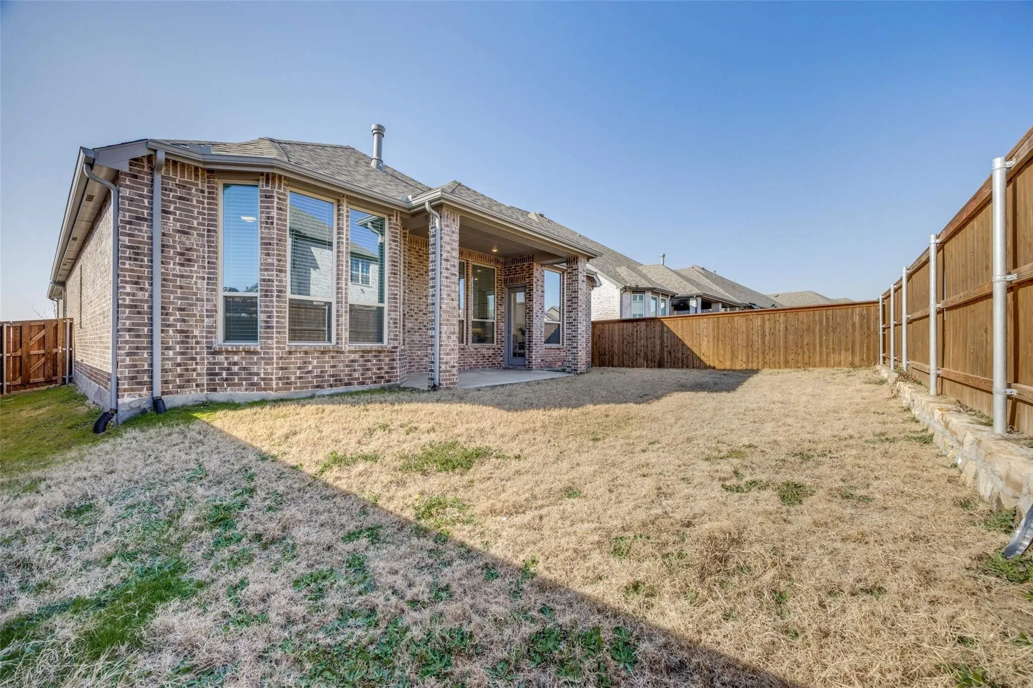 Back of property featuring brick siding, a fenced backyard, and a patio