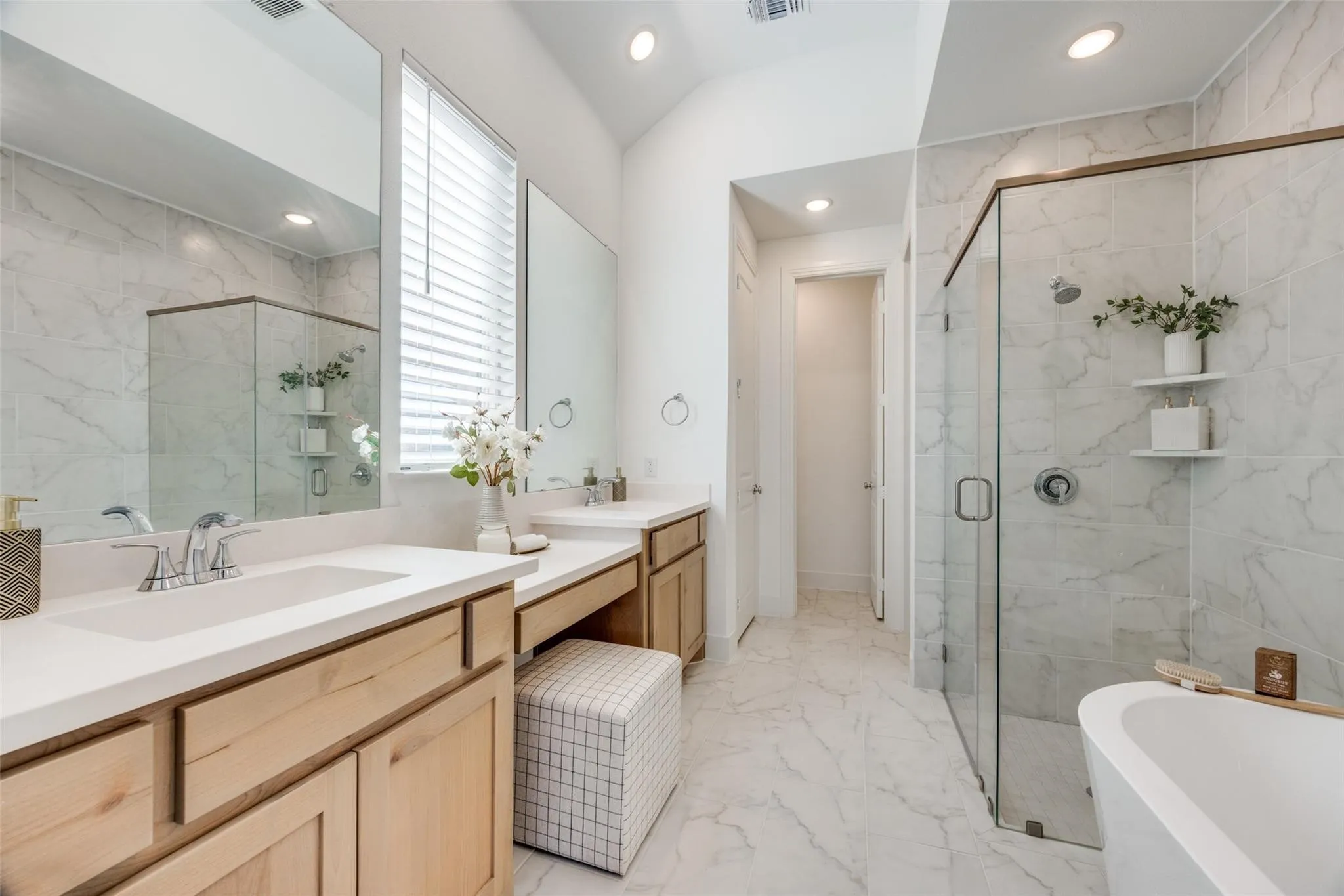 Bathroom with marble tiled floors, a stall shower, a freestanding tub, two vanities, and recessed lighting