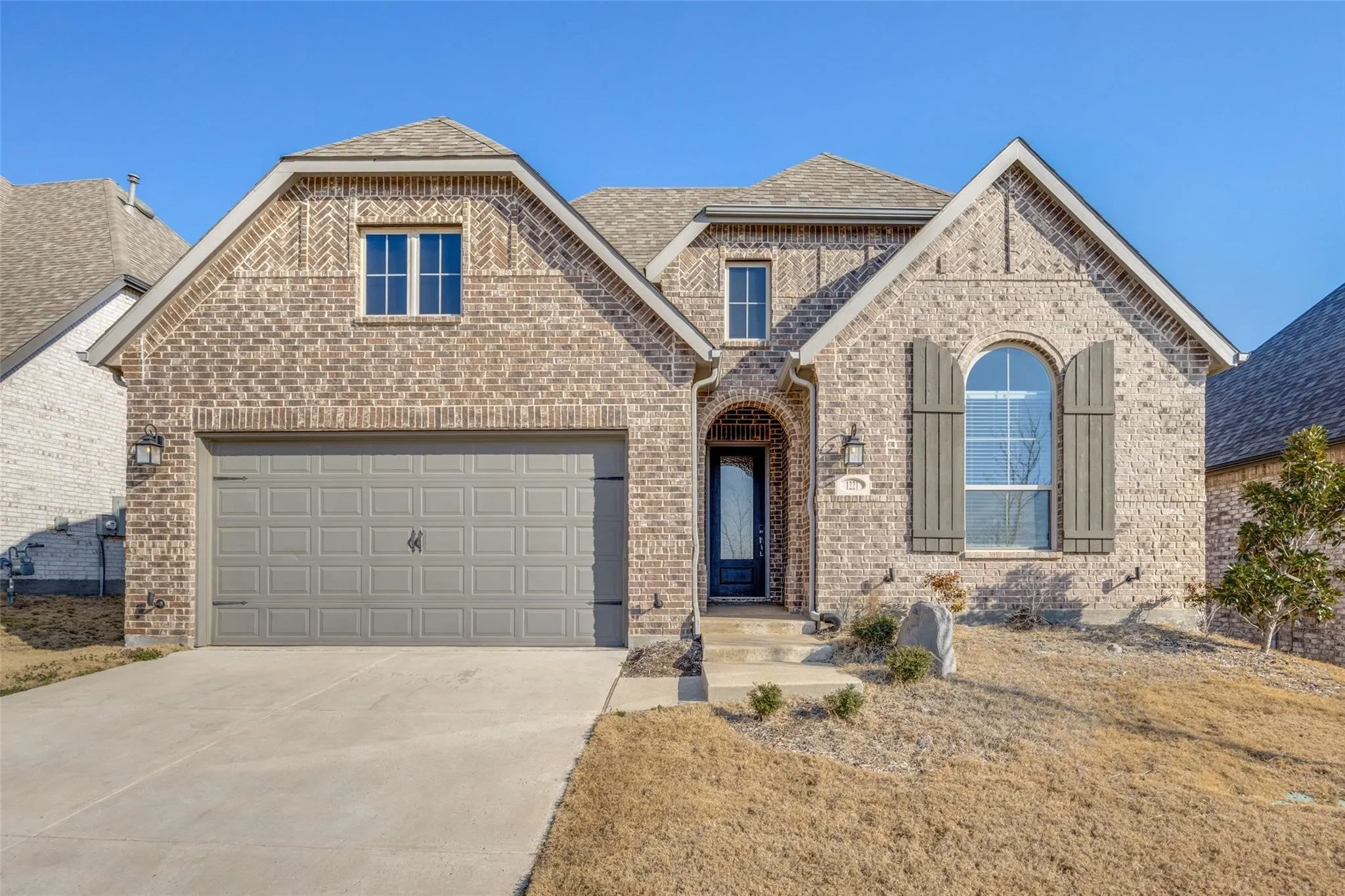 French country home with brick siding, driveway, a shingled roof, and an attached garage
