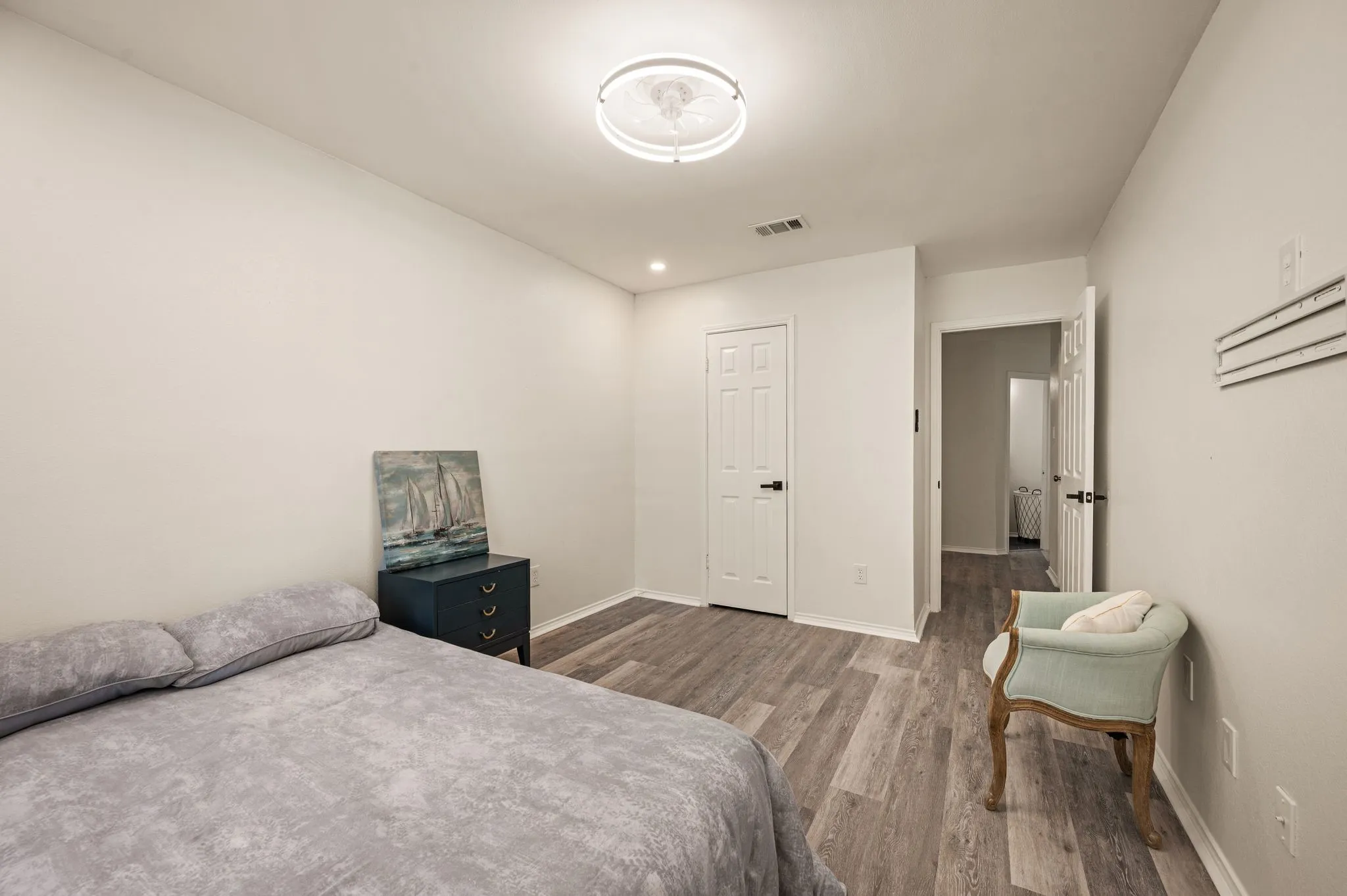 Wood-finish flooring throughout, white walls, and a recessed ceiling light