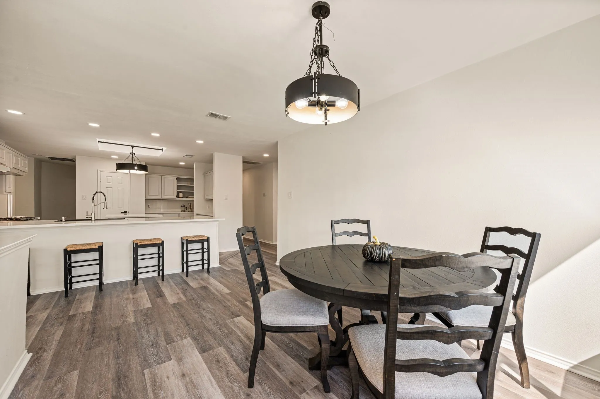 Open-concept living space featuring wood-finish flooring, recessed lighting, and a kitchen island with a built-in sink and gooseneck faucet