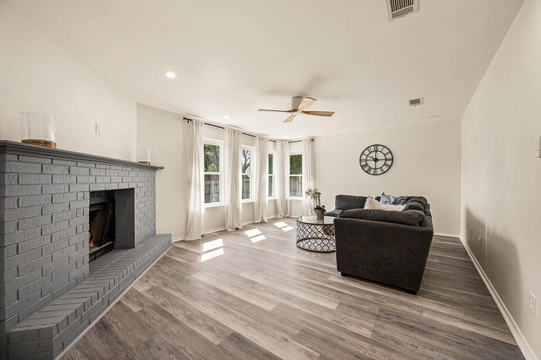 Living area featuring a painted brick fireplace, wood-finish flooring, recessed lighting, and a ceiling fan