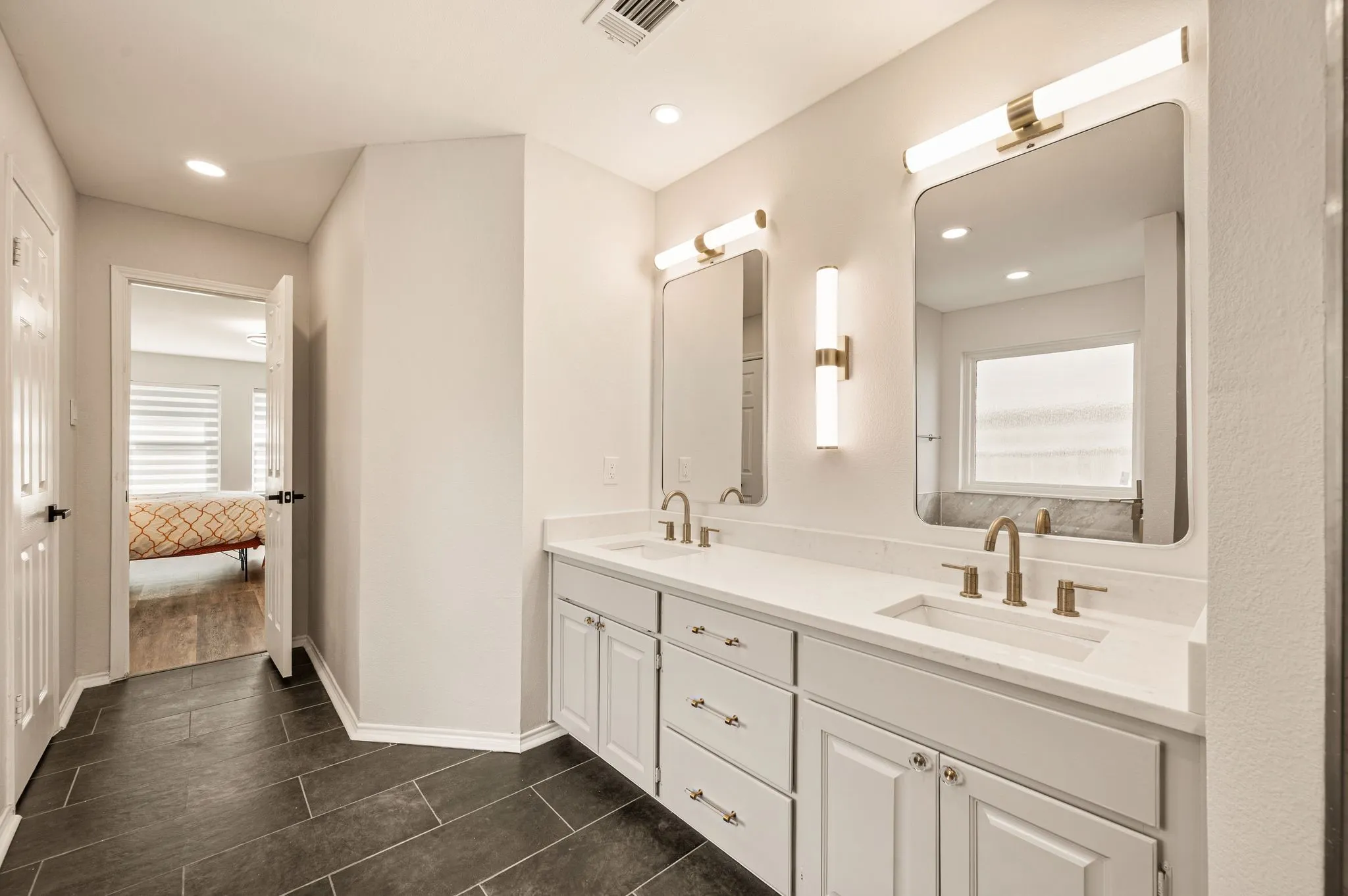 Dual vanity featuring white shaker cabinetry, white countertops, and gold-finish hardware