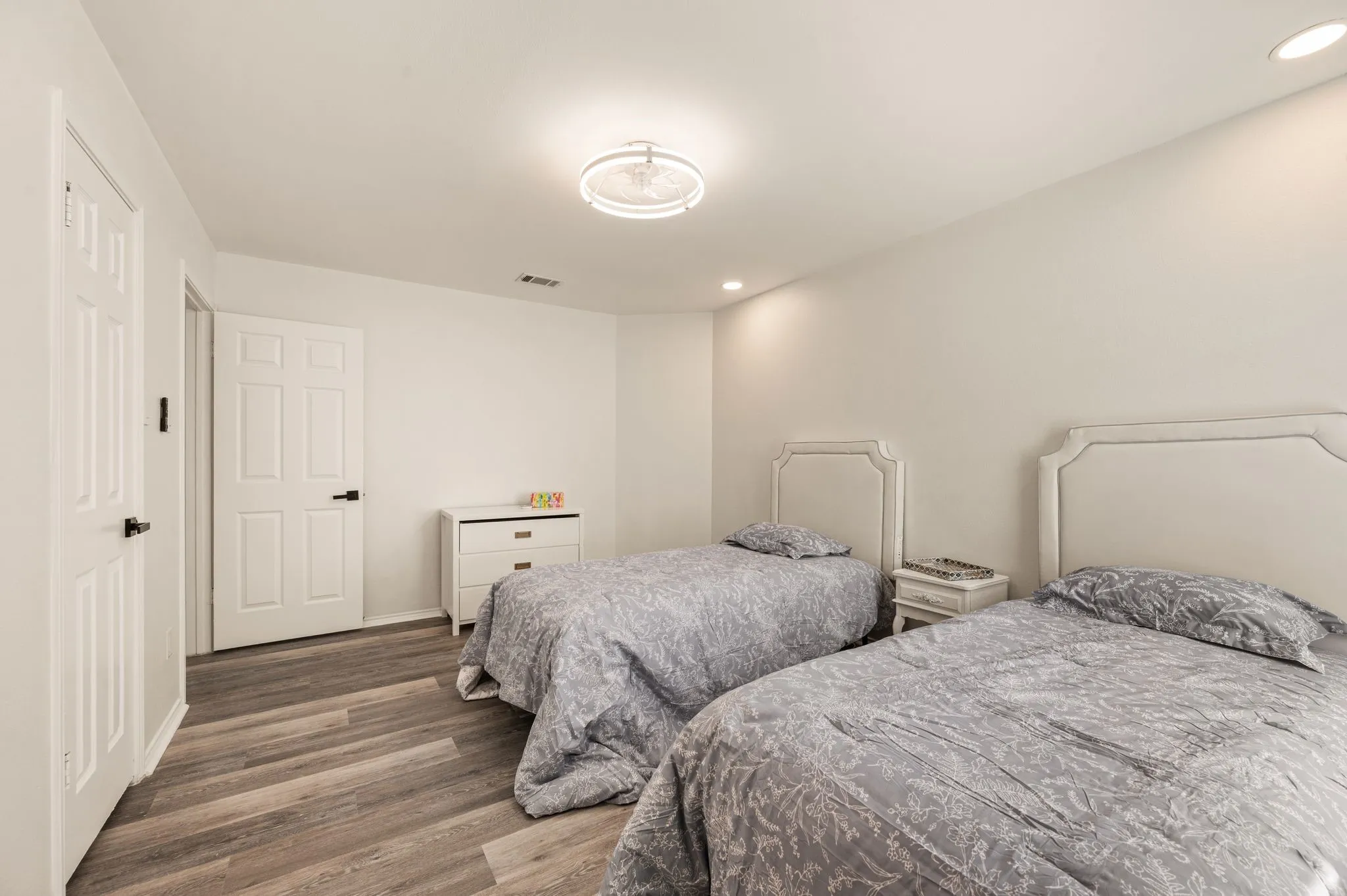 Recessed lighting, wood-finish flooring, and white walls create a bright interior