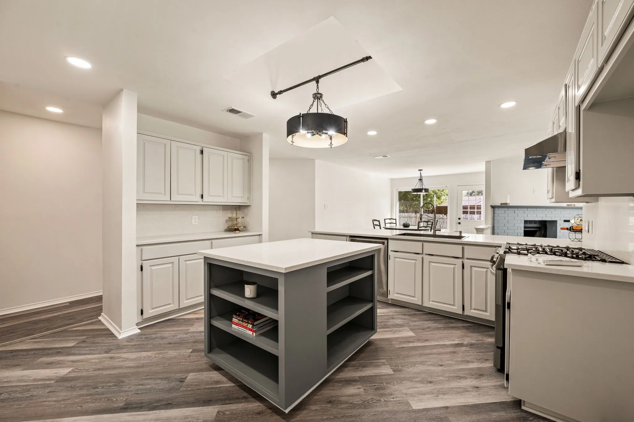 Spacious kitchen featuring an island with open shelving, wood-finish flooring, recessed lighting, and white cabinetry