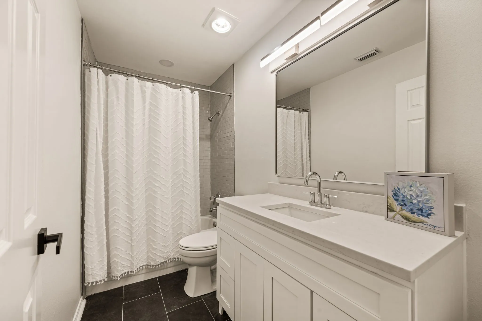 White vanity with a single basin sink, polished chrome faucet, and integrated countertop