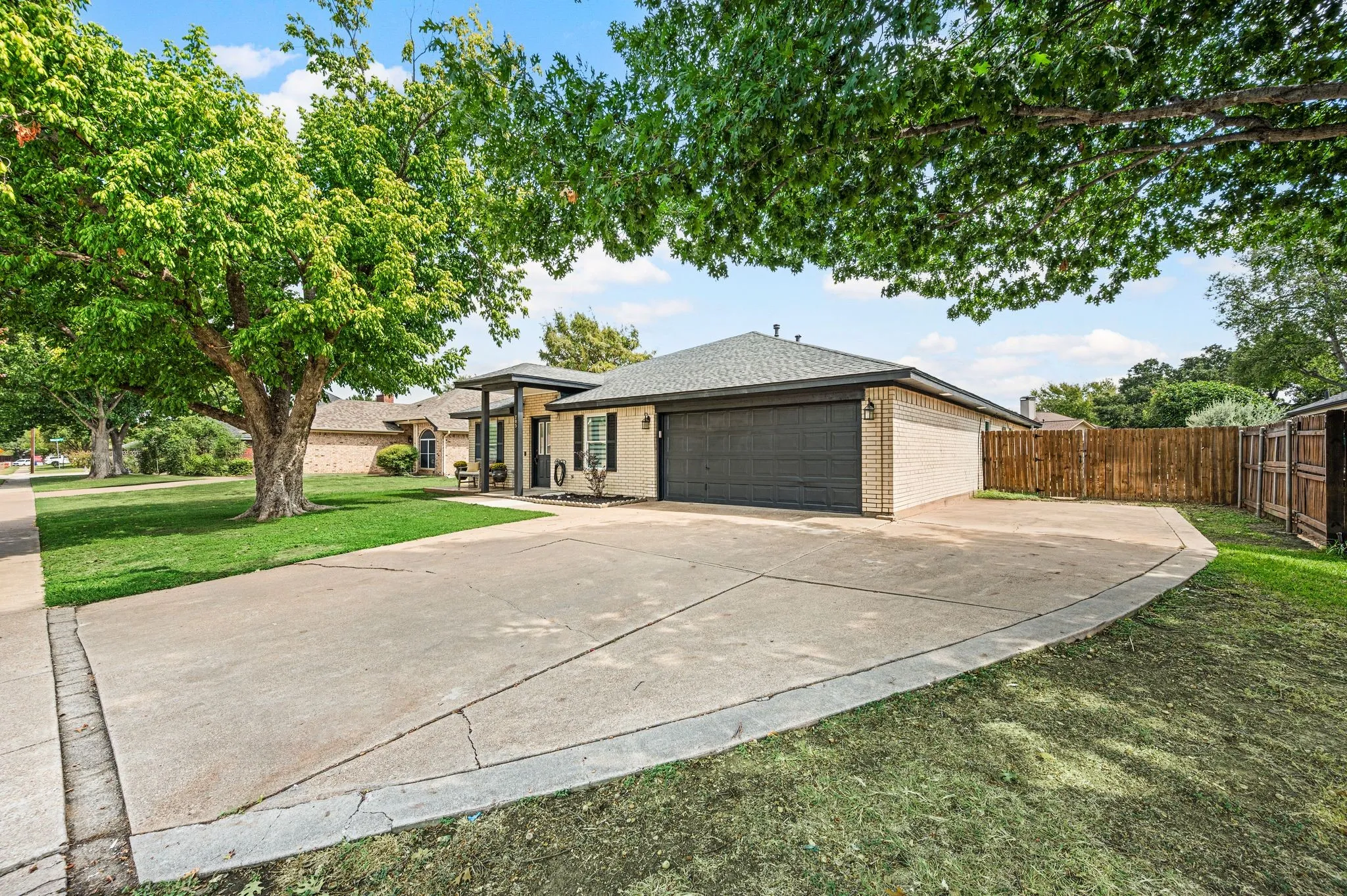 Brick exterior residence featuring an attached garage, covered entryway, and a paved driveway