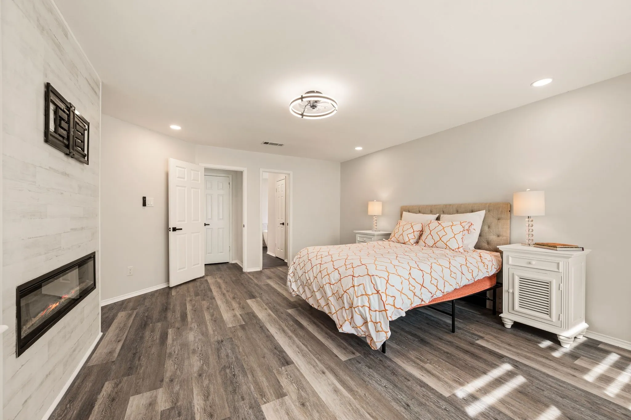 Wood-finish flooring, recessed lighting, and a modern linear fireplace with a textured surround