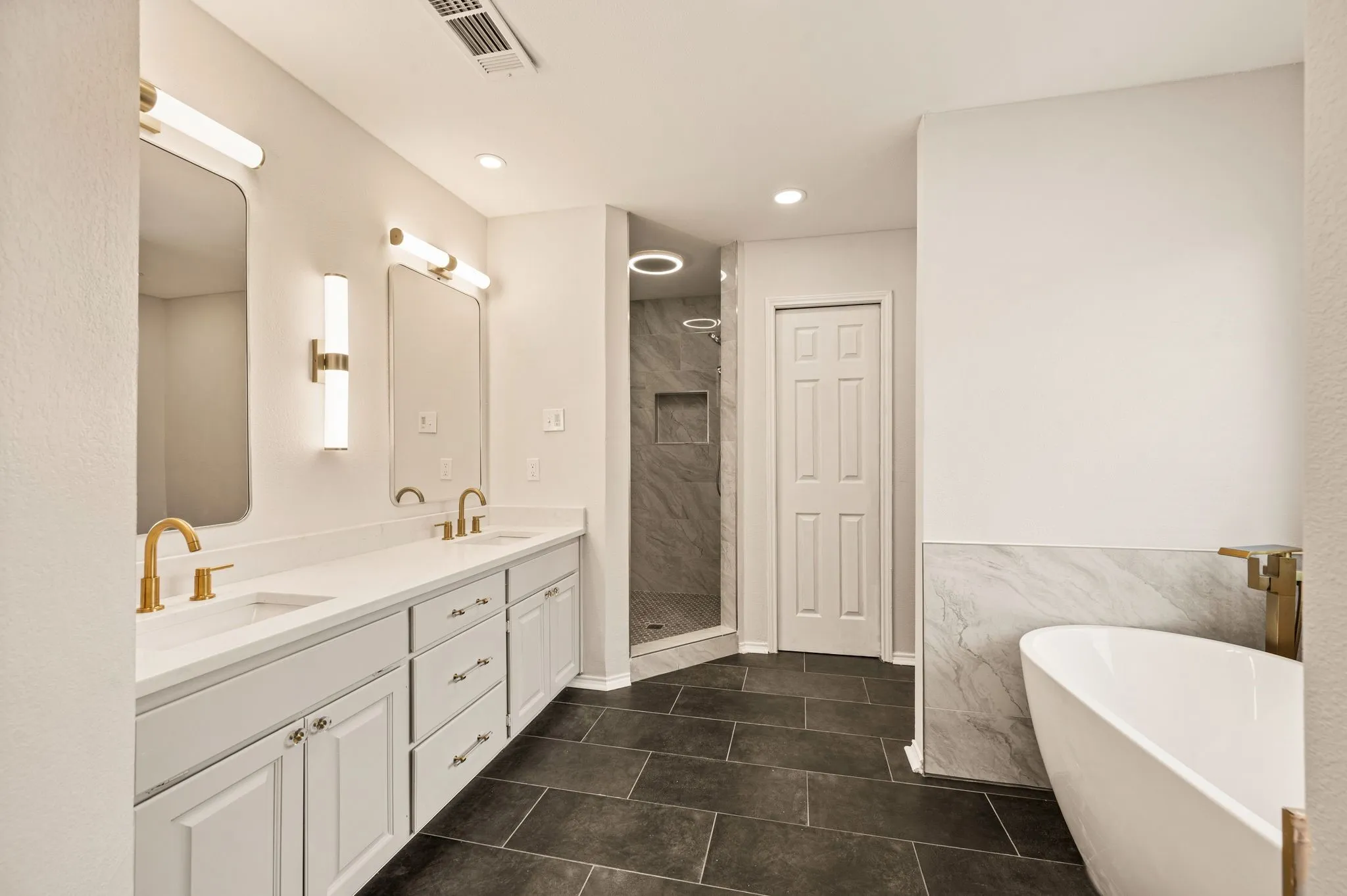 Dual vanity with white cabinetry and countertop, gold-finish fixtures, and rectangular mirrors