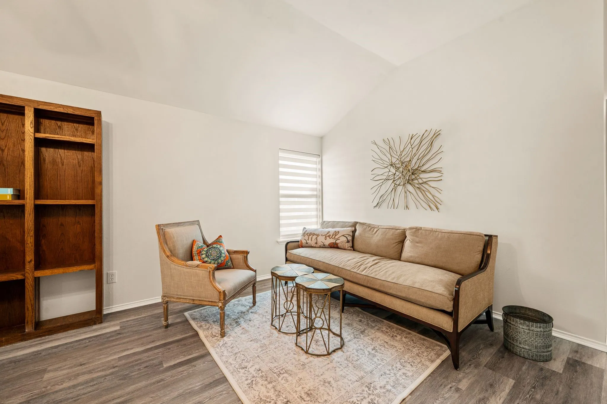 Vaulted ceiling, wood-finish flooring, built-in shelving, and window with blinds