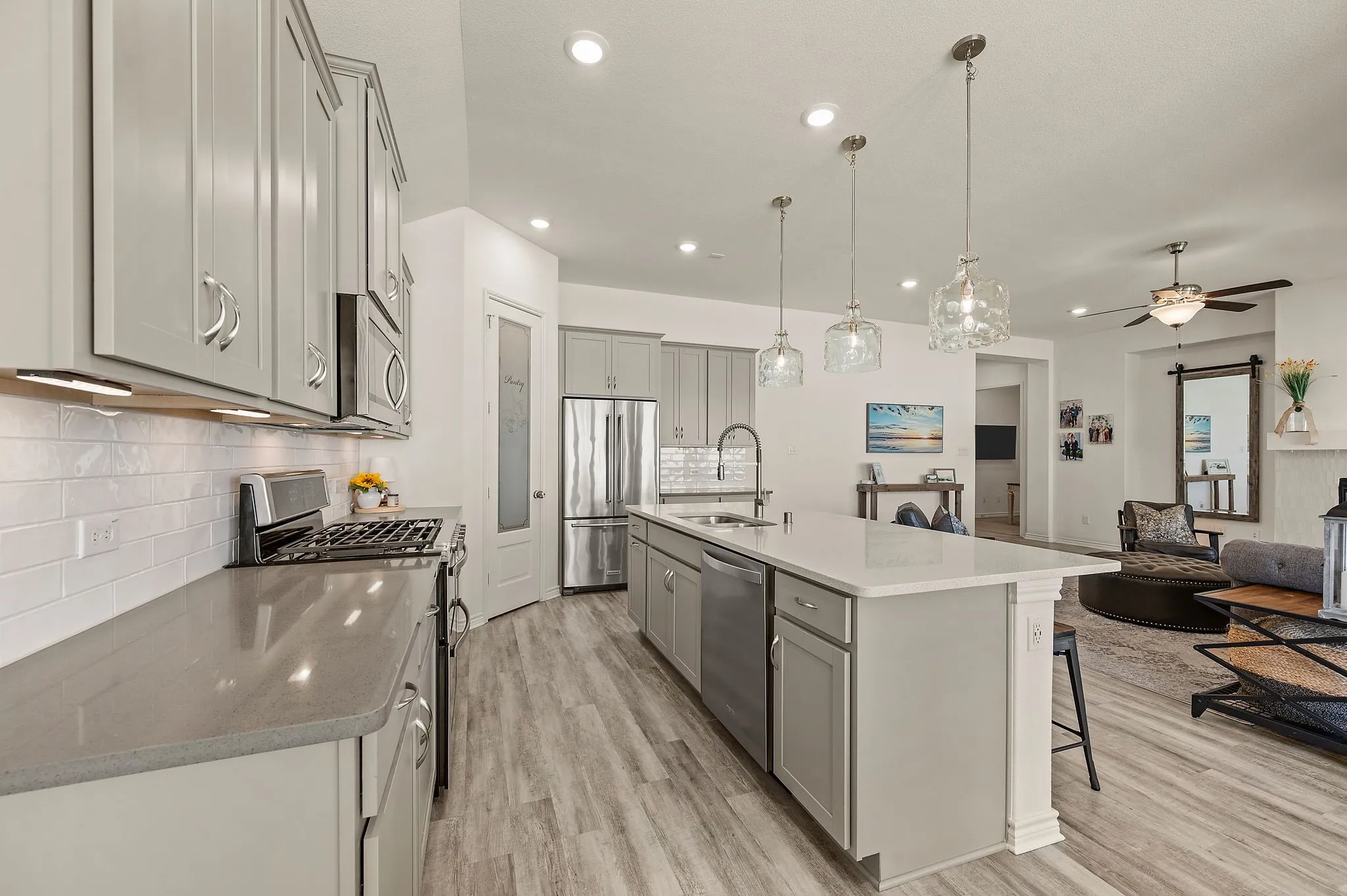 Open-concept kitchen featuring so much cabinetry so you will have plenty of storage, stainless steel appliances including a gas stove, a large island with quartz & beautiful pendant lighting,