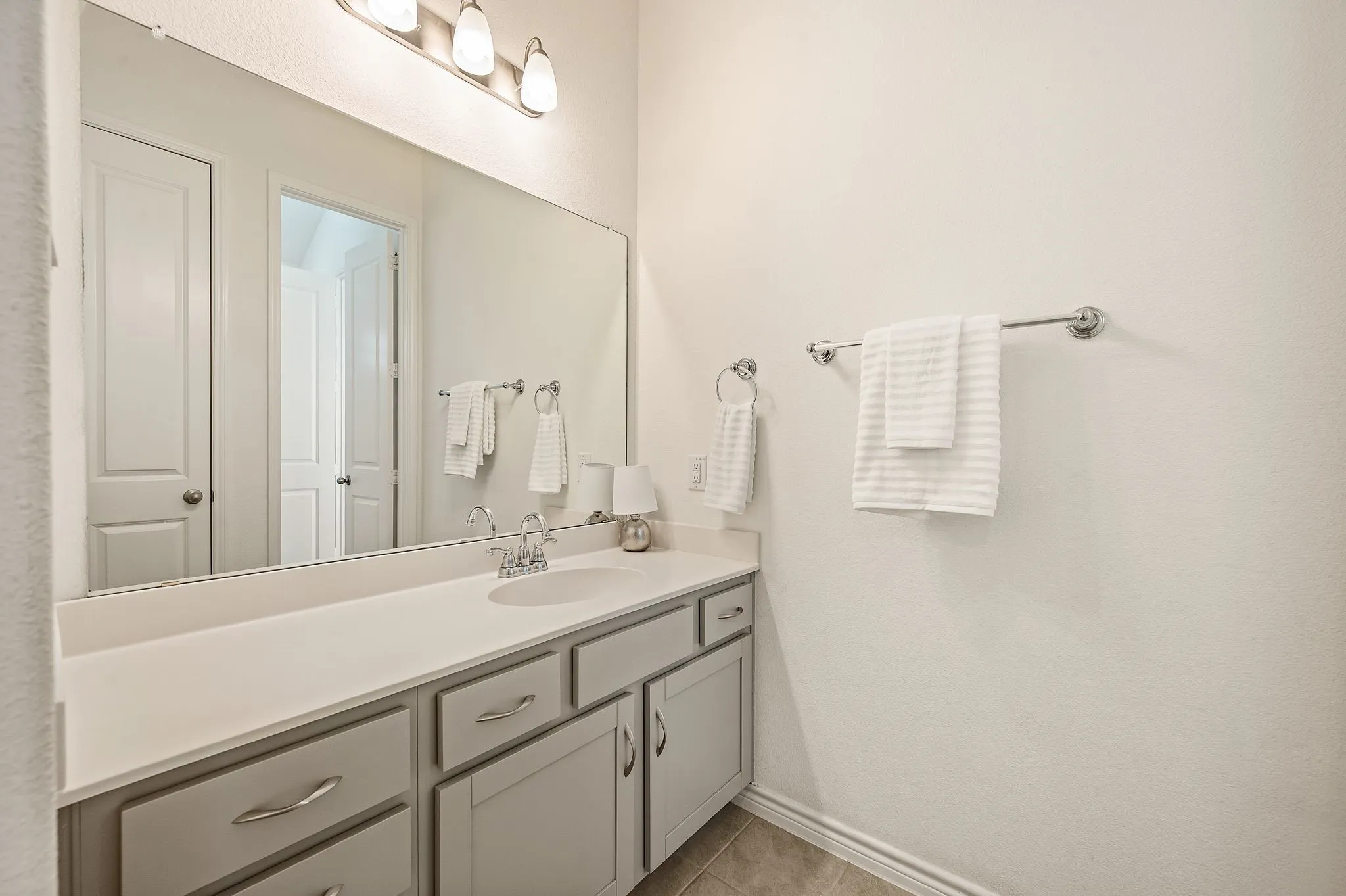 Built-in vanity with a single basin sink, light-toned countertop, and light gray cabinetry