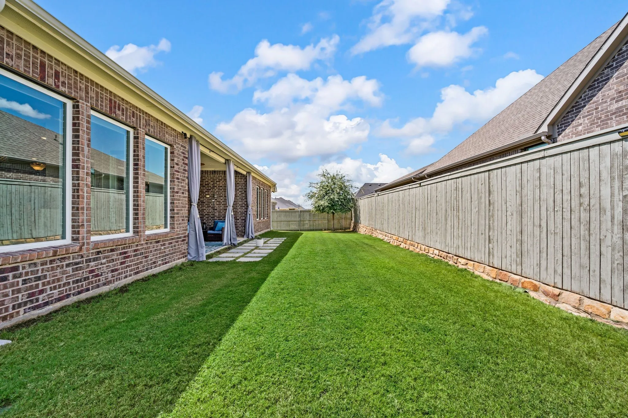 Expansive backyard with a fabulous manicured lawn, wonderful covered patio, and a wood fence with stone base...a perfect place to enjoy time with family and friends!