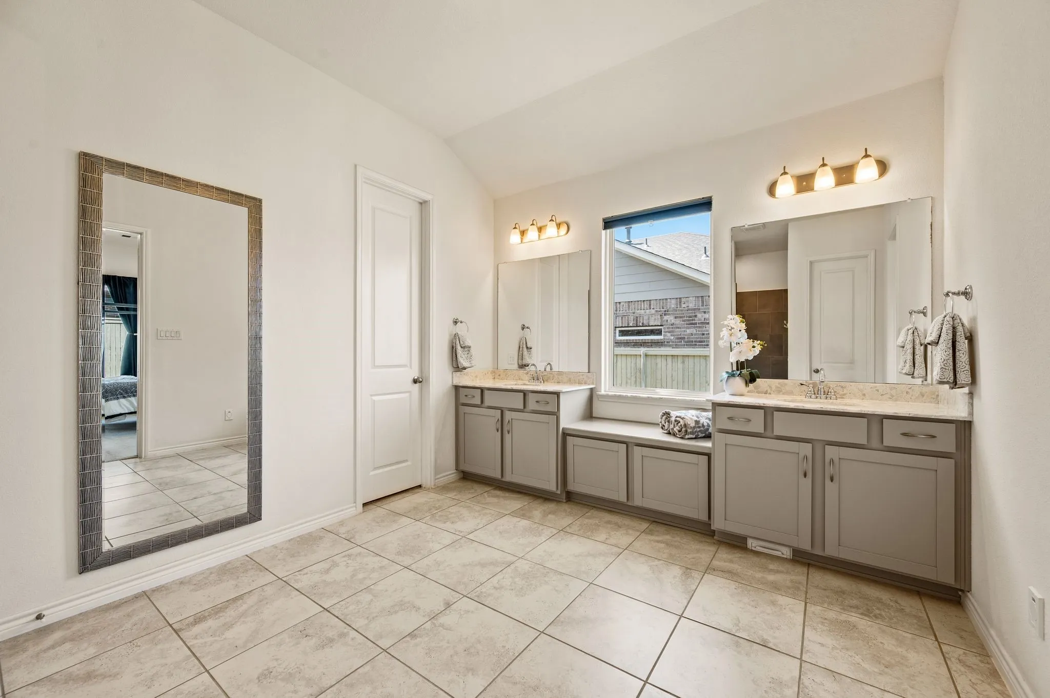Primary bathroom with dual vanities and lots of  cabinets for great storage, really beautiful tile flooring, and a window for natural light. This bathroom gives you room to move about and not be right next to each other!