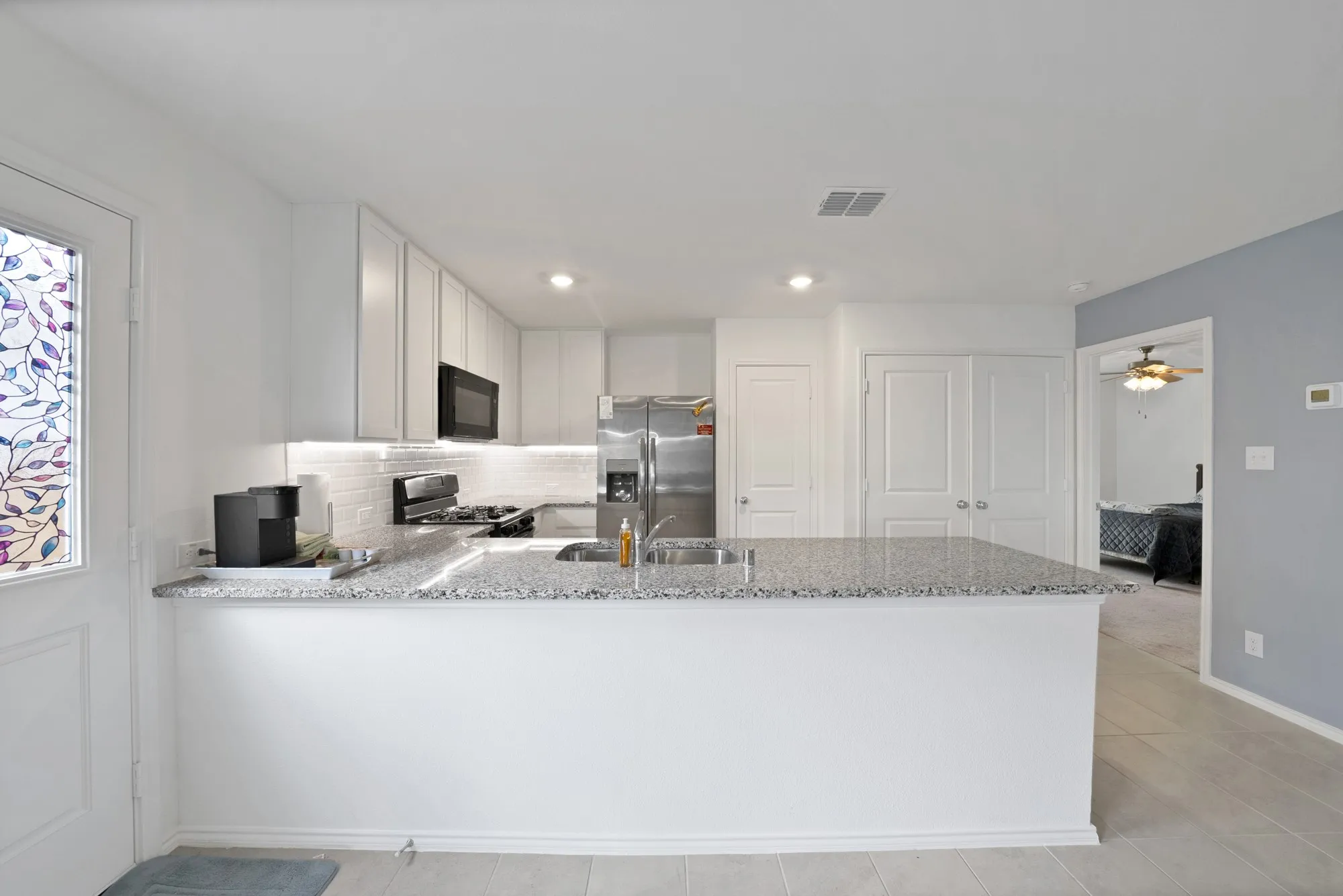 Kitchen featuring white cabinetry, a large center island with a sink, stainless steel appliances, and tile flooring