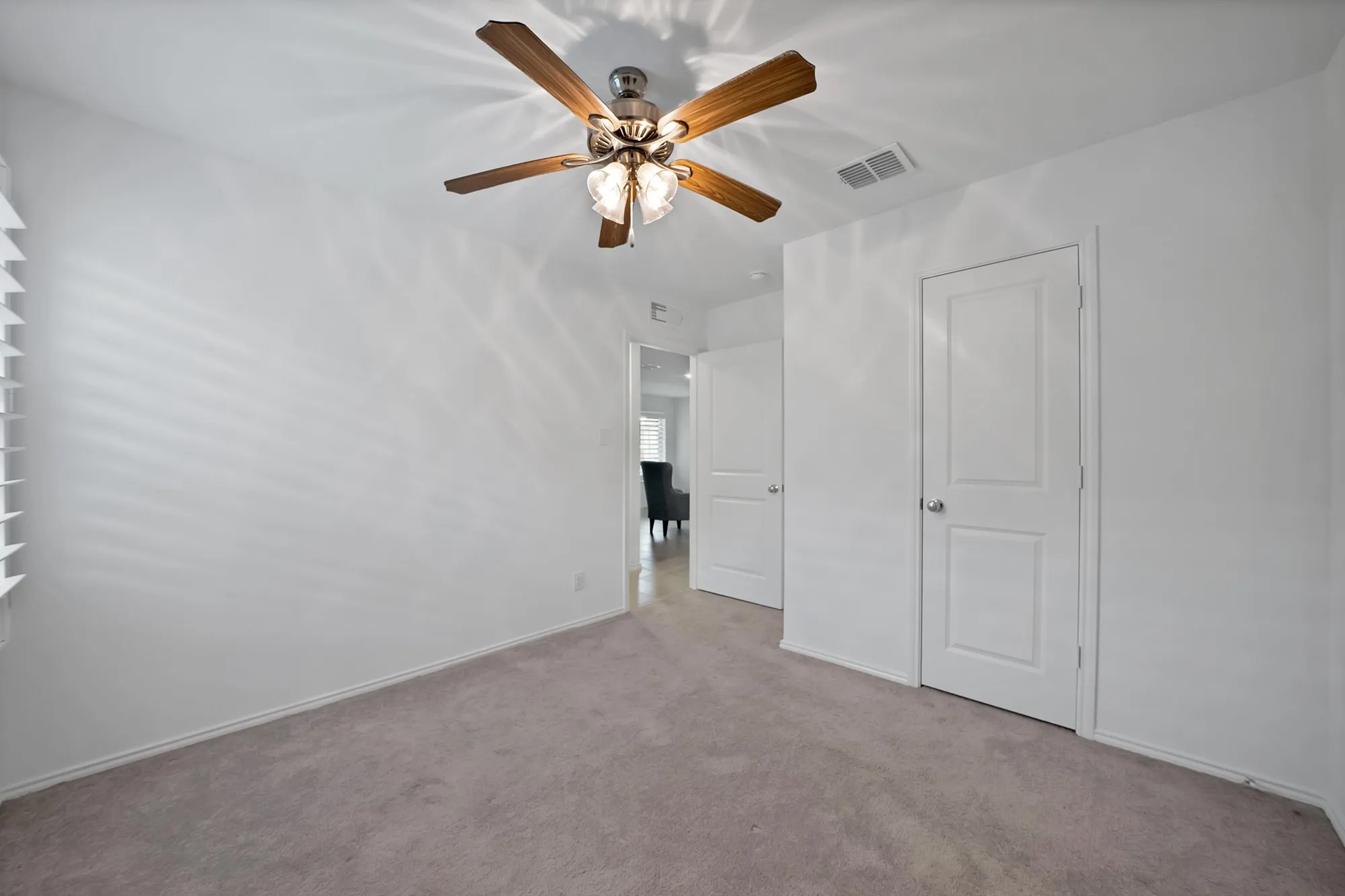 Neutral-toned carpeting, white walls, and a ceiling fan with light fixture