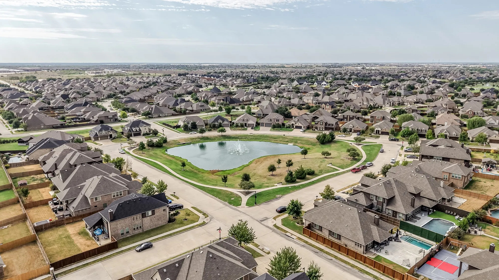 Community featuring a central pond with fountain, surrounding green space, and extensive residential development