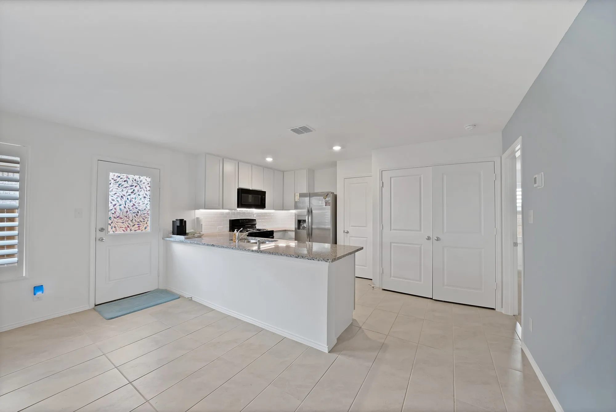 Kitchen featuring white cabinetry, granite countertops, stainless steel appliances, and tile flooring