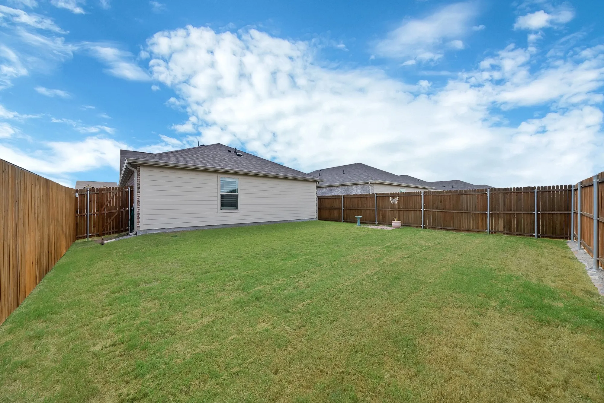 Expansive green lawn with complete wood privacy fencing, and a side exterior of the property