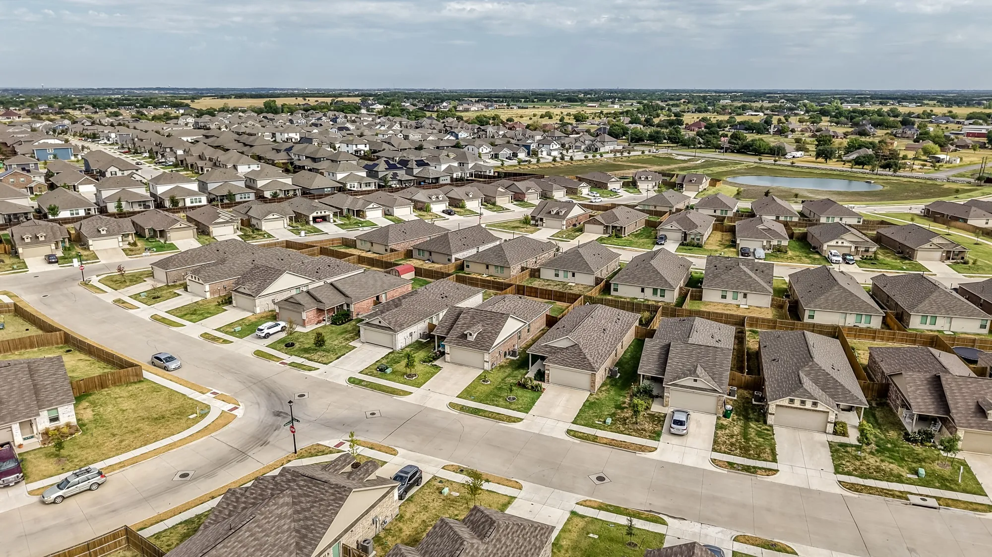 Residential street with single-family homes, concrete driveways, and privacy fencing
