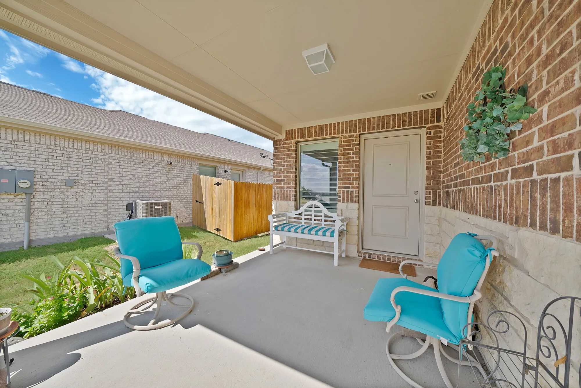 Covered concrete patio featuring a brick wall with stone detailing