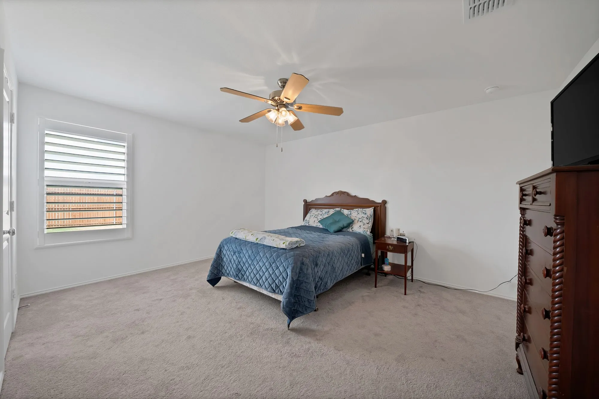 Neutral wall color, light-toned carpet, and a ceiling fan with integrated lighting