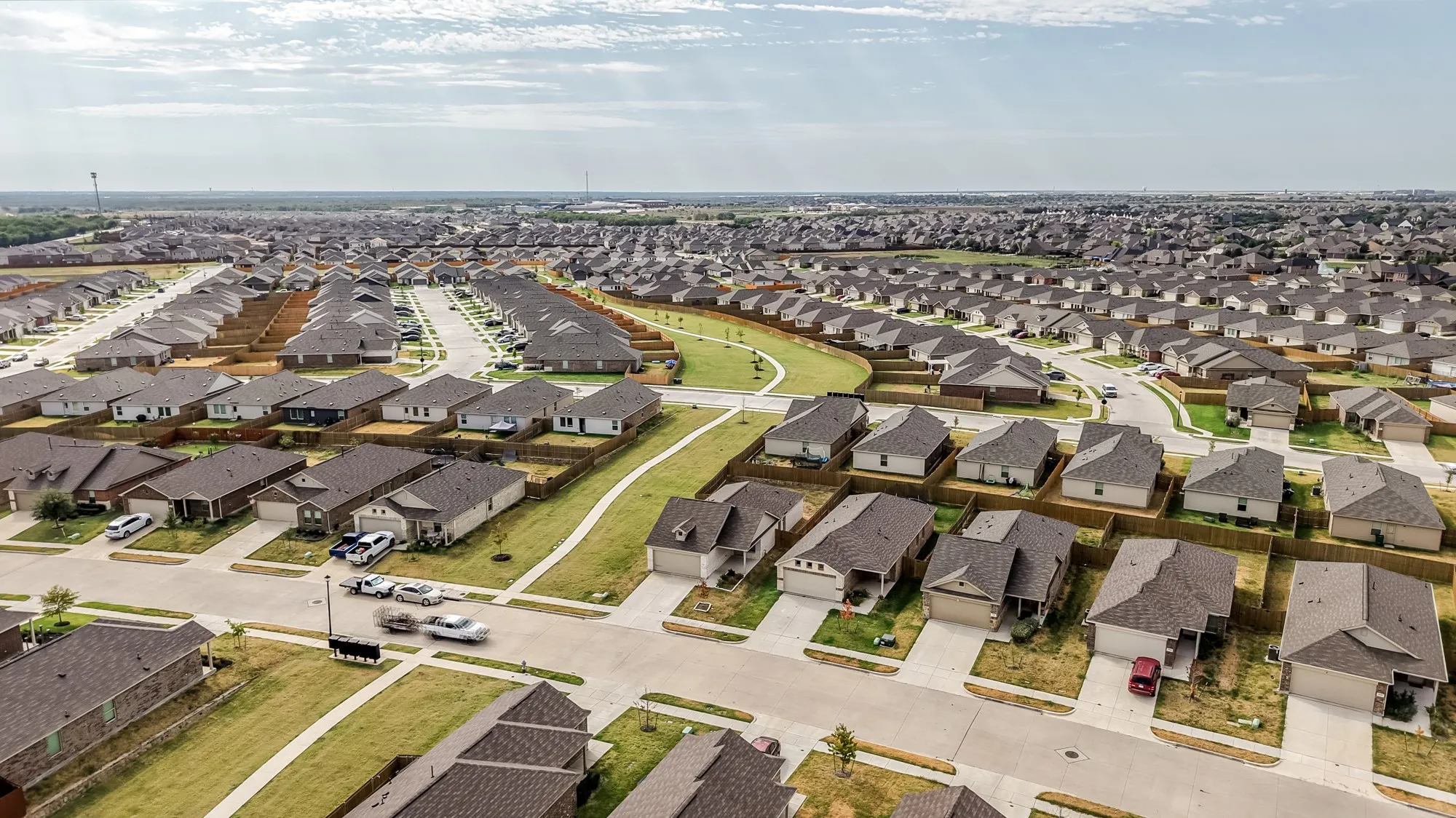 Expansive residential development featuring numerous single-family homes, paved streets, and green spaces