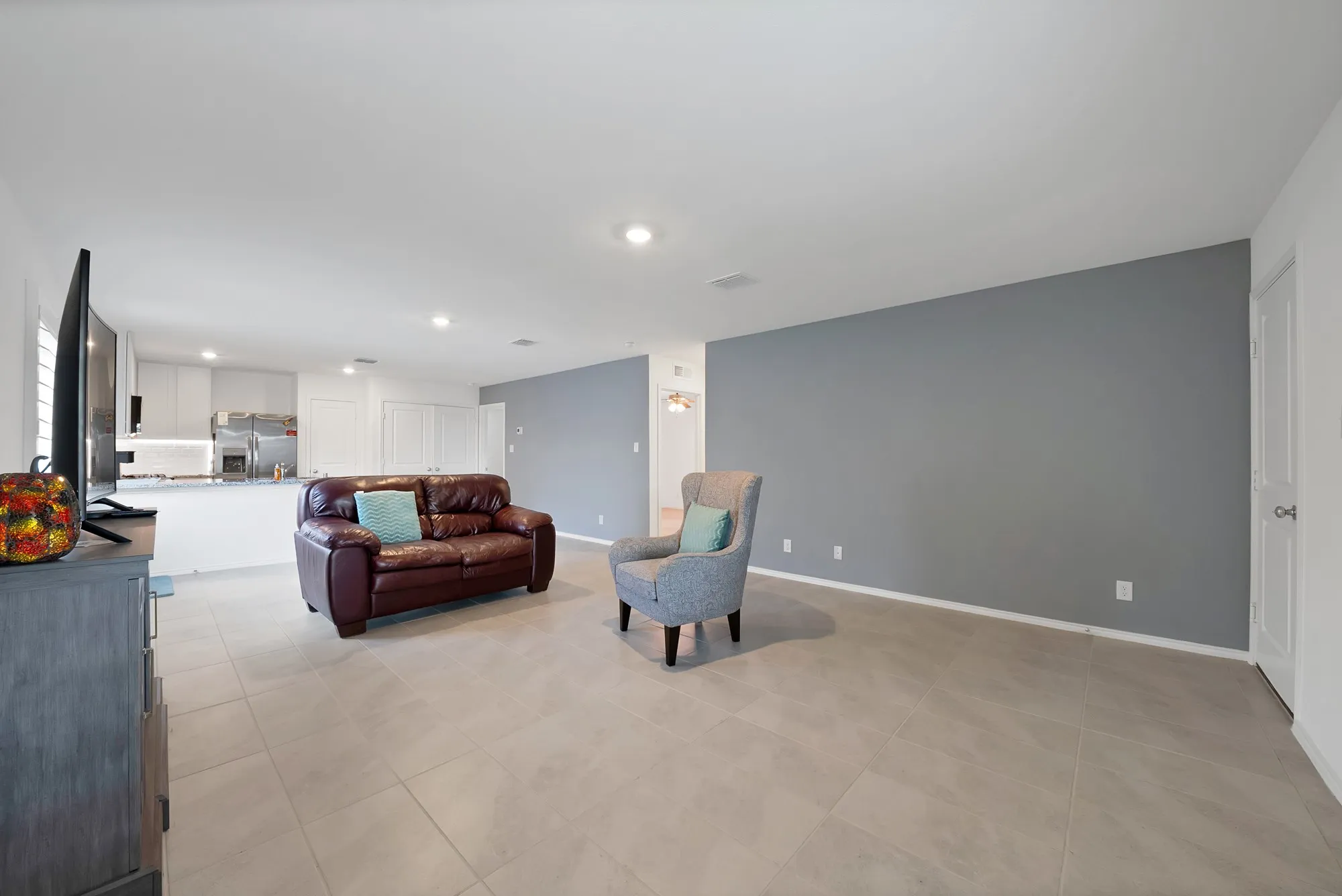 Expansive living area with large format tile flooring, recessed lighting, and a gray accent wall