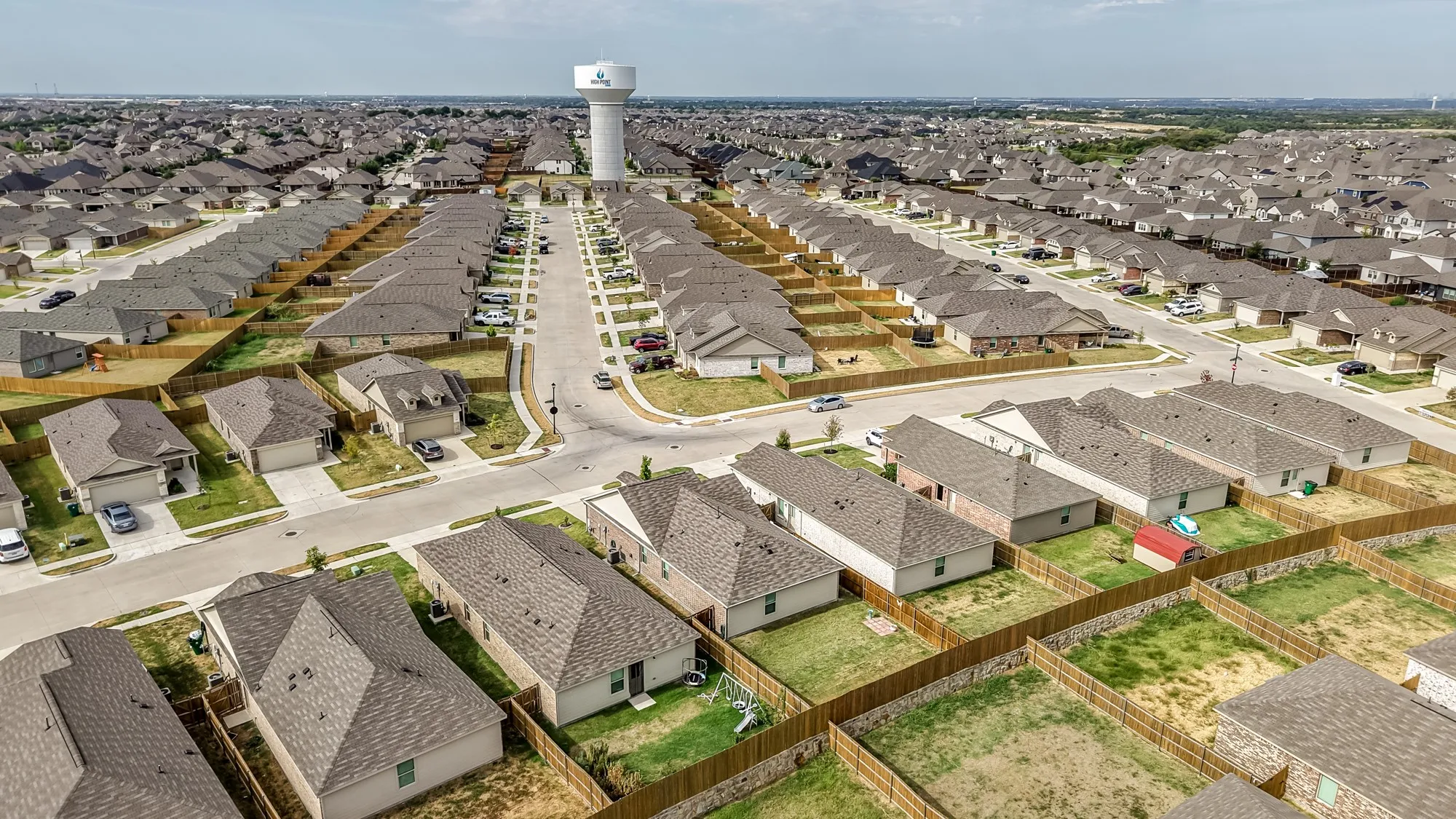 Expansive residential community featuring numerous single-story homes with pitched roofs and fenced backyards