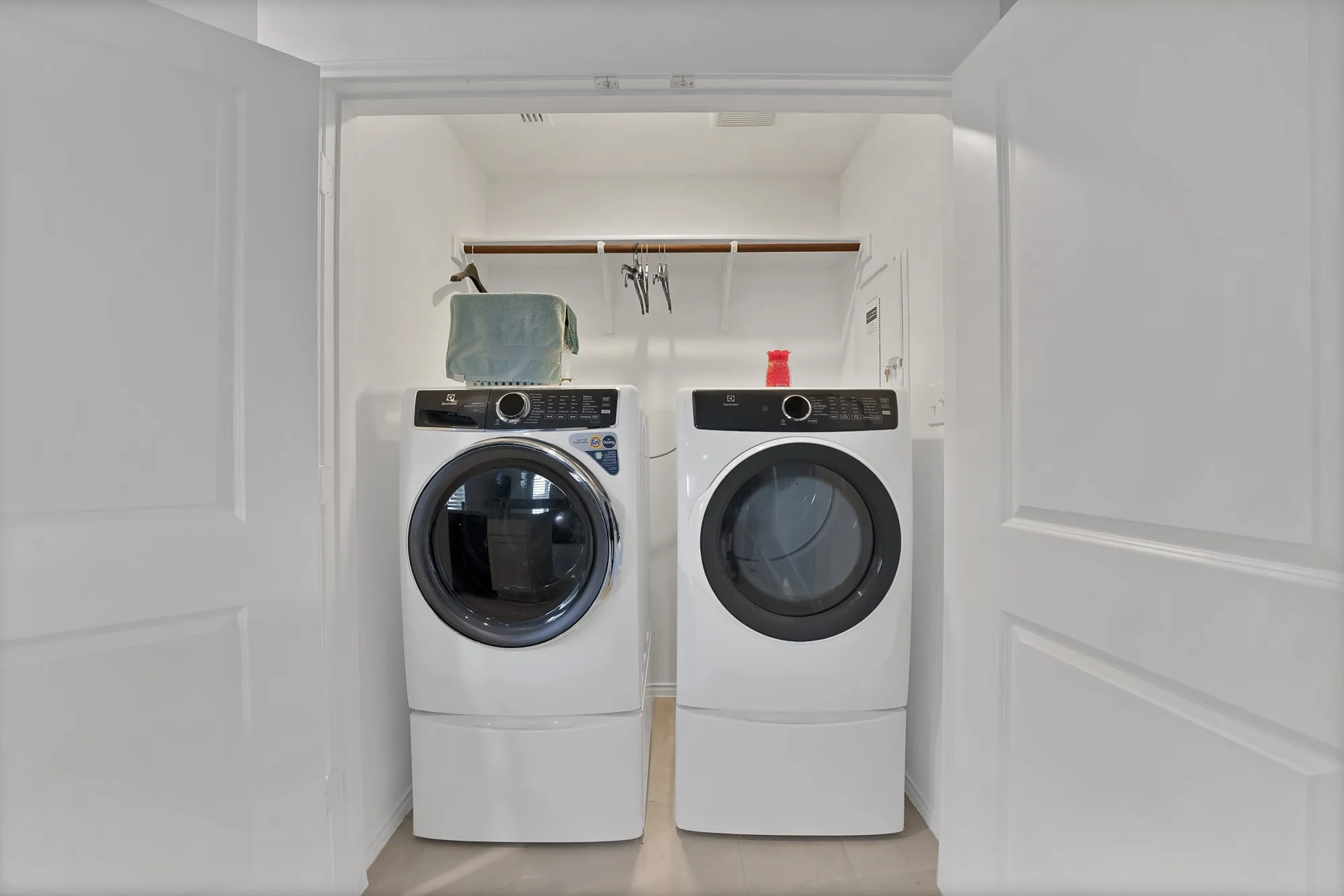 Dedicated laundry closet with wood-finish flooring and a built-in shelving unit