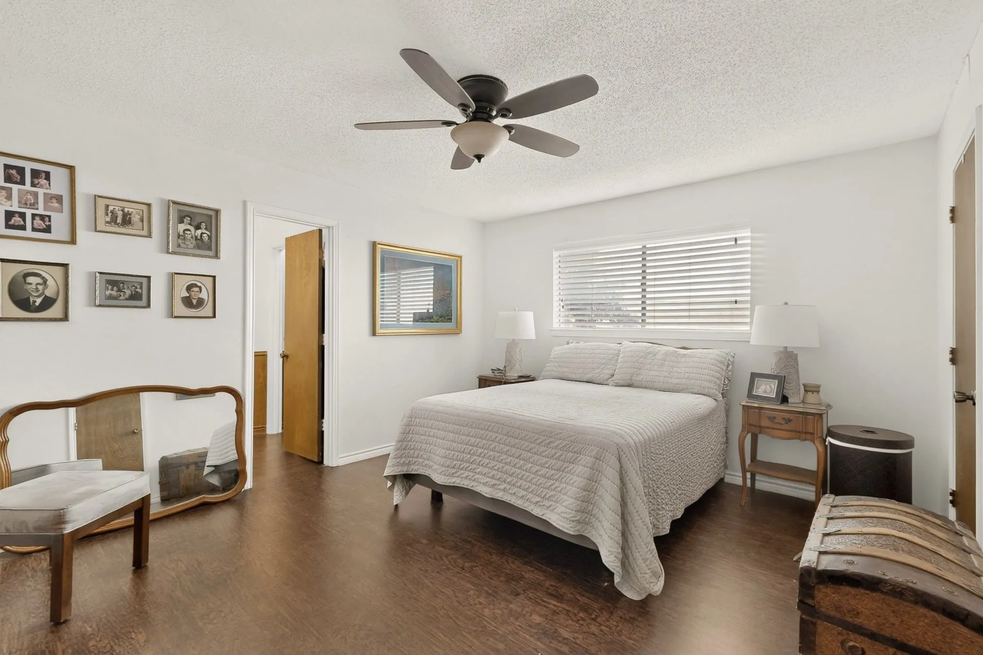 Wood-finish flooring throughout, white walls, and a ceiling fan with integrated lighting