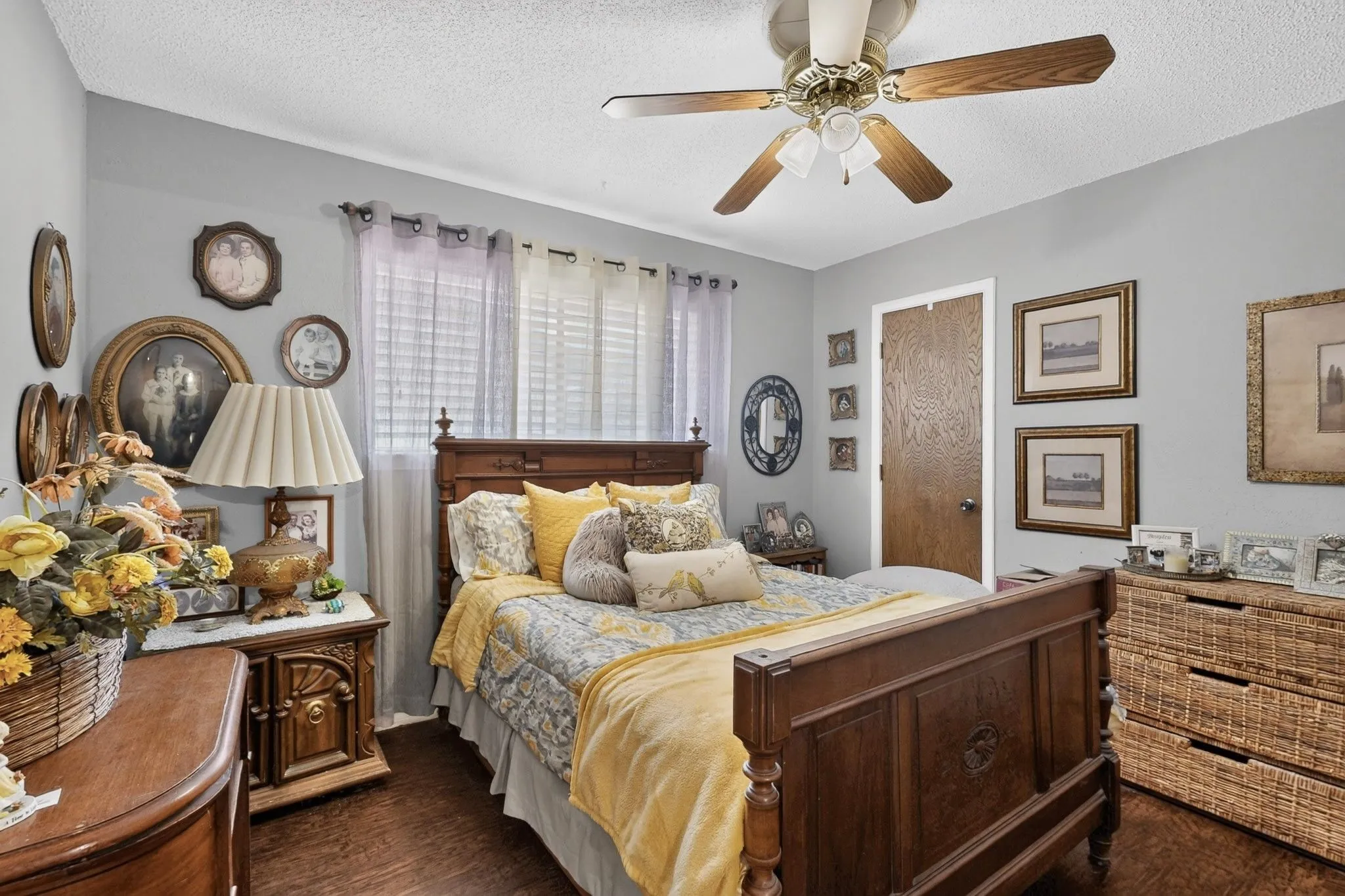 Wood-finish flooring with light gray walls, a ceiling fan with light fixture, and a solid interior door