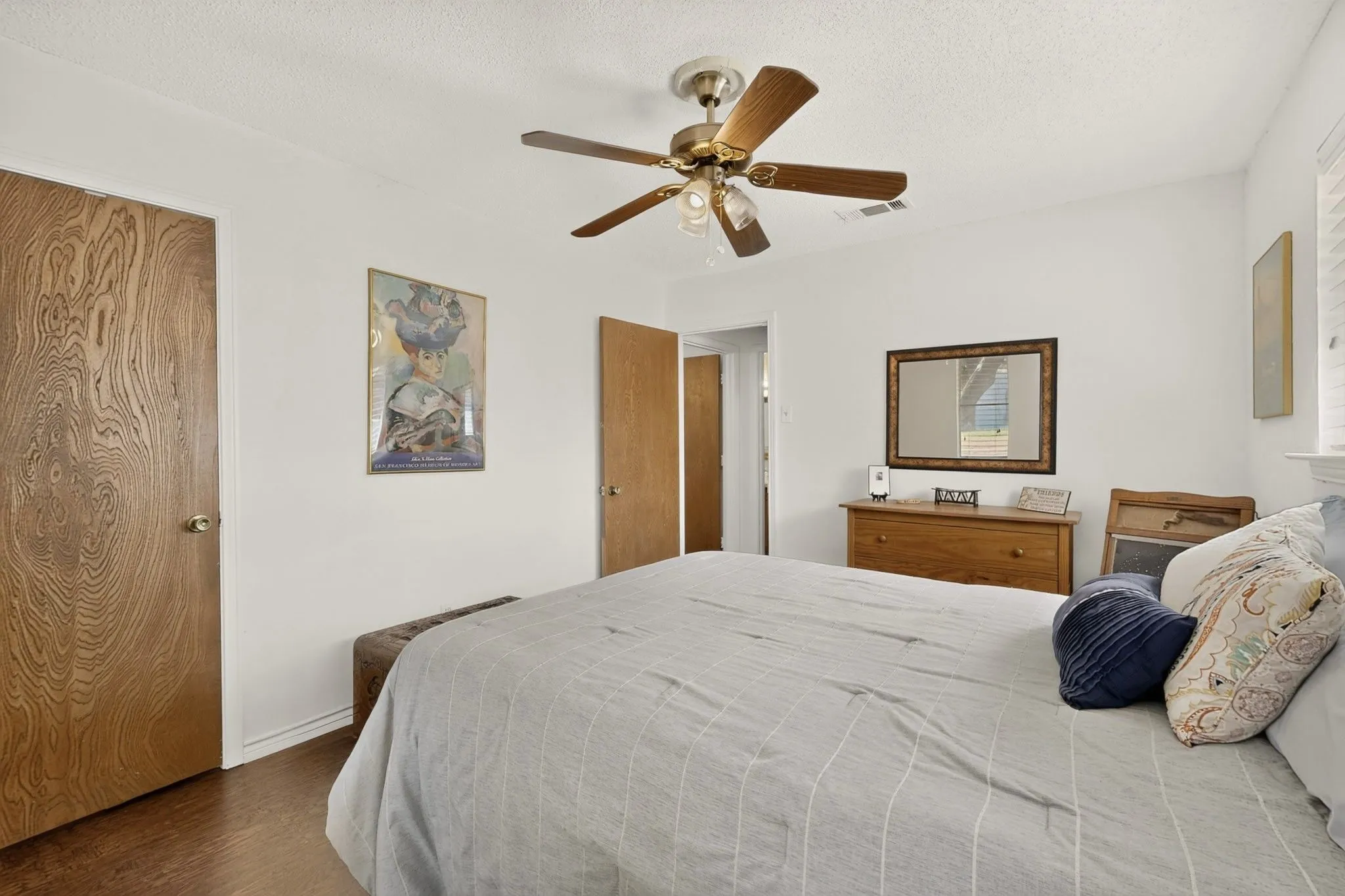 Wood-finish flooring, ceiling fan with integrated lighting, wood-finish interior doors, and white walls